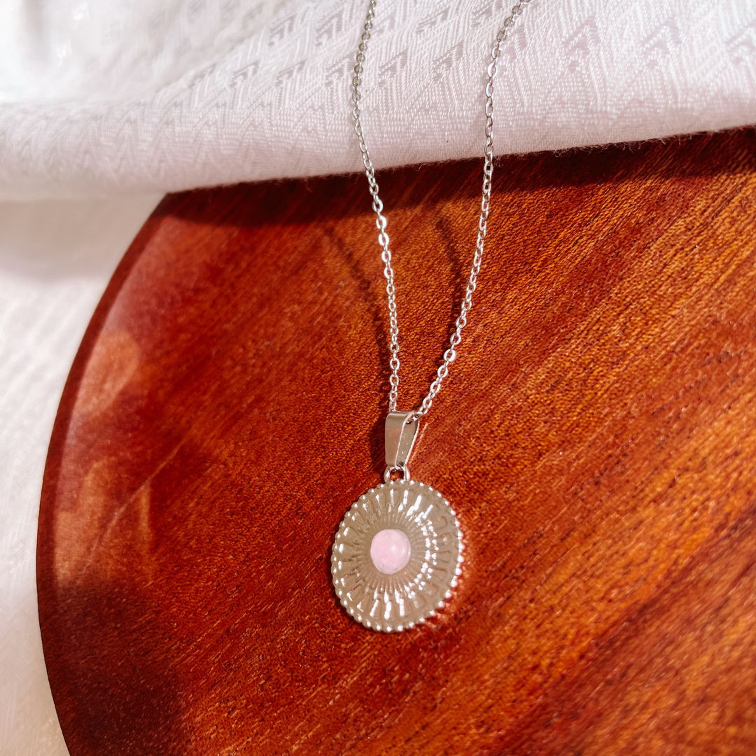 Handgemachte rosa Rosenquarz-Kette mit rundem Medaillon Anhänger in Silber, liegend auf Tablett