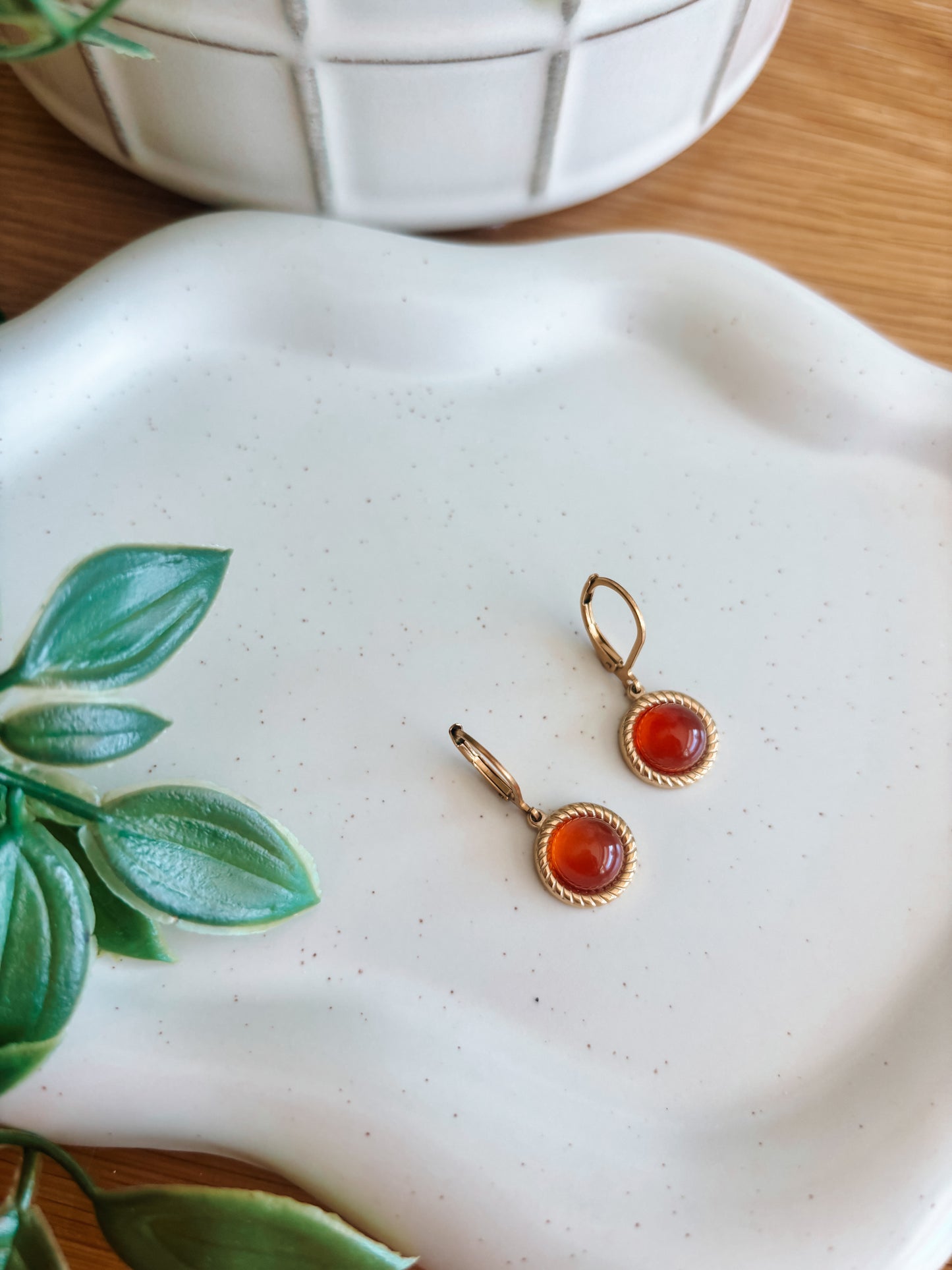 Goldene Creolen-Ohrringe mit runden, roten Karneol-Steinen auf Tablett, seitlich