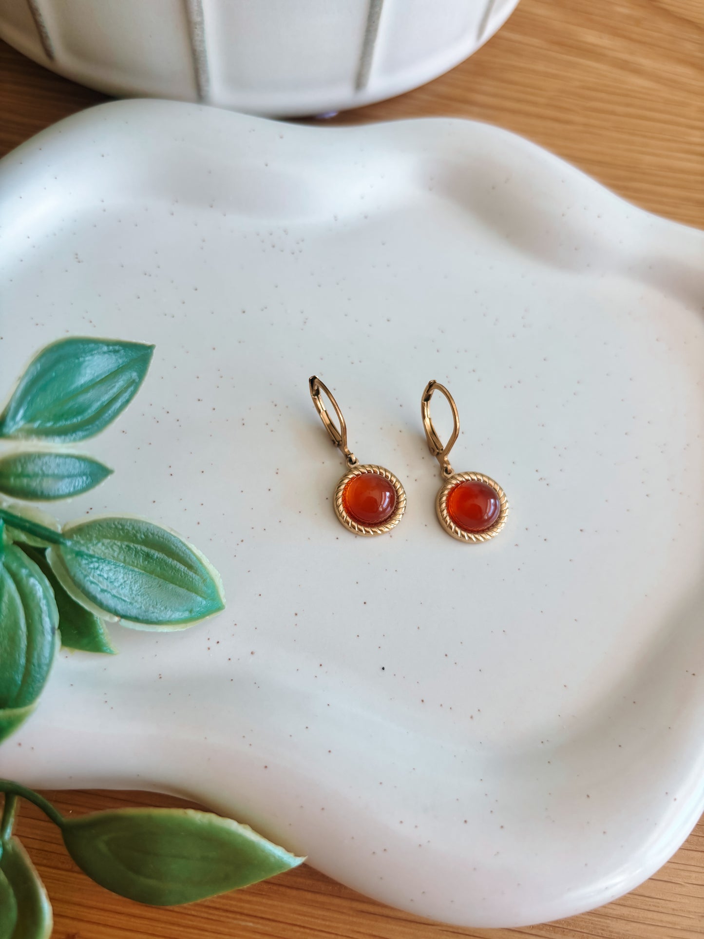 Goldene Creolen-Ohrringe mit runden, roten Karneol-Steinen auf Tablett