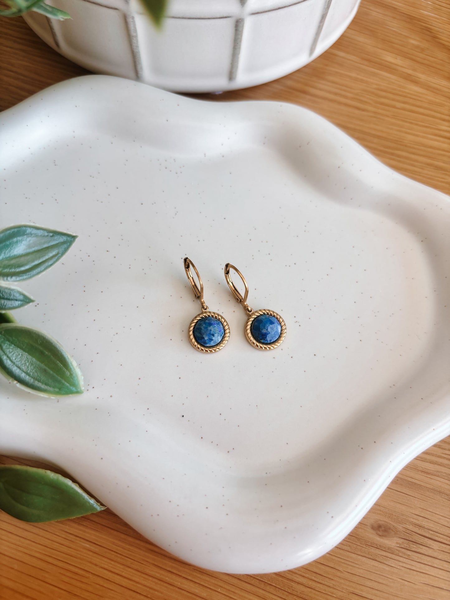 Goldene Creolen-Ohrringe mit runden, facettierten, blauen Lapislazuli-Steinen auf Tablett