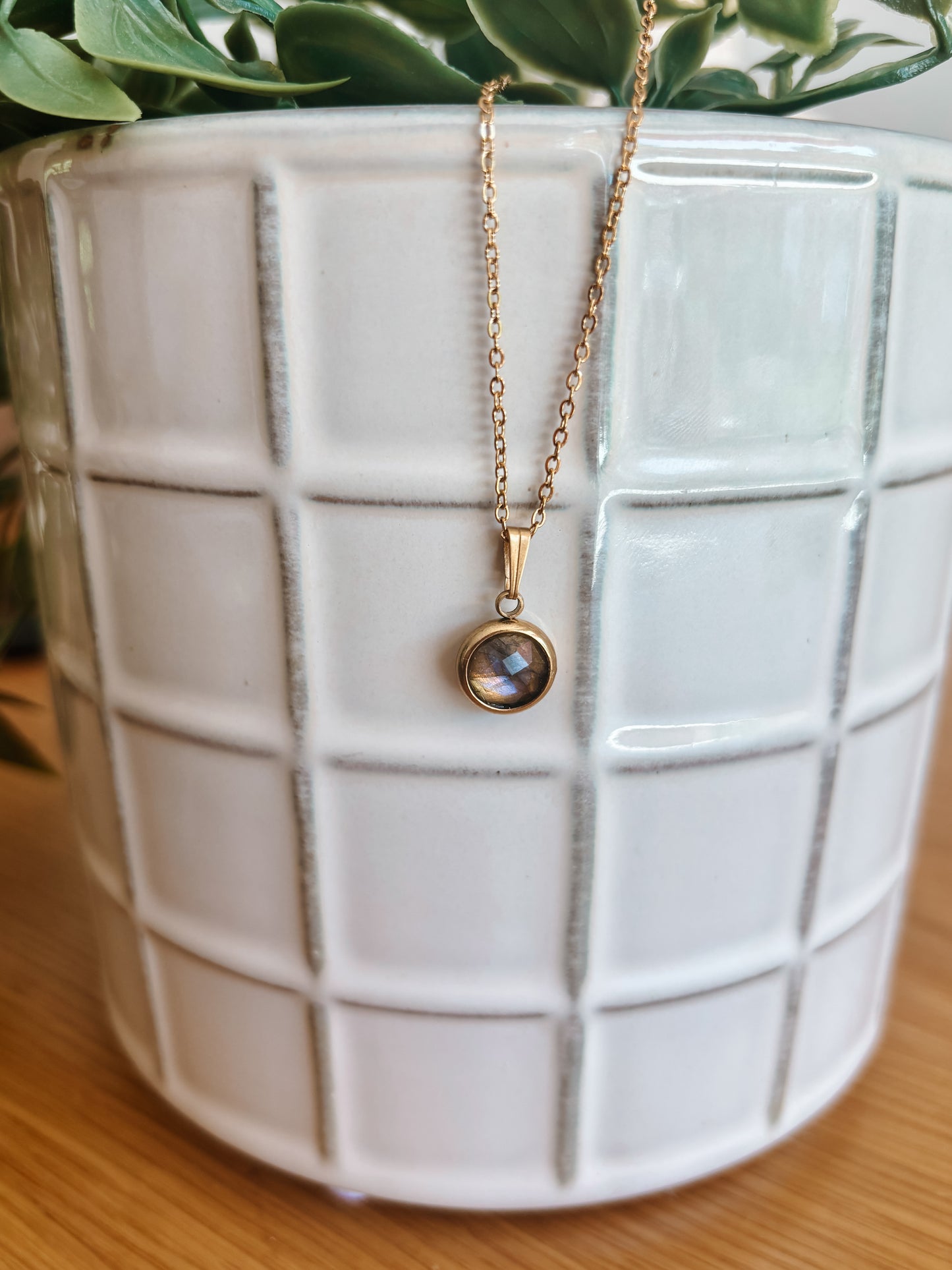 Handgemachte graue Labradorit-Kette mit ovalem Anhänger in Gold, hängend an einer Vase