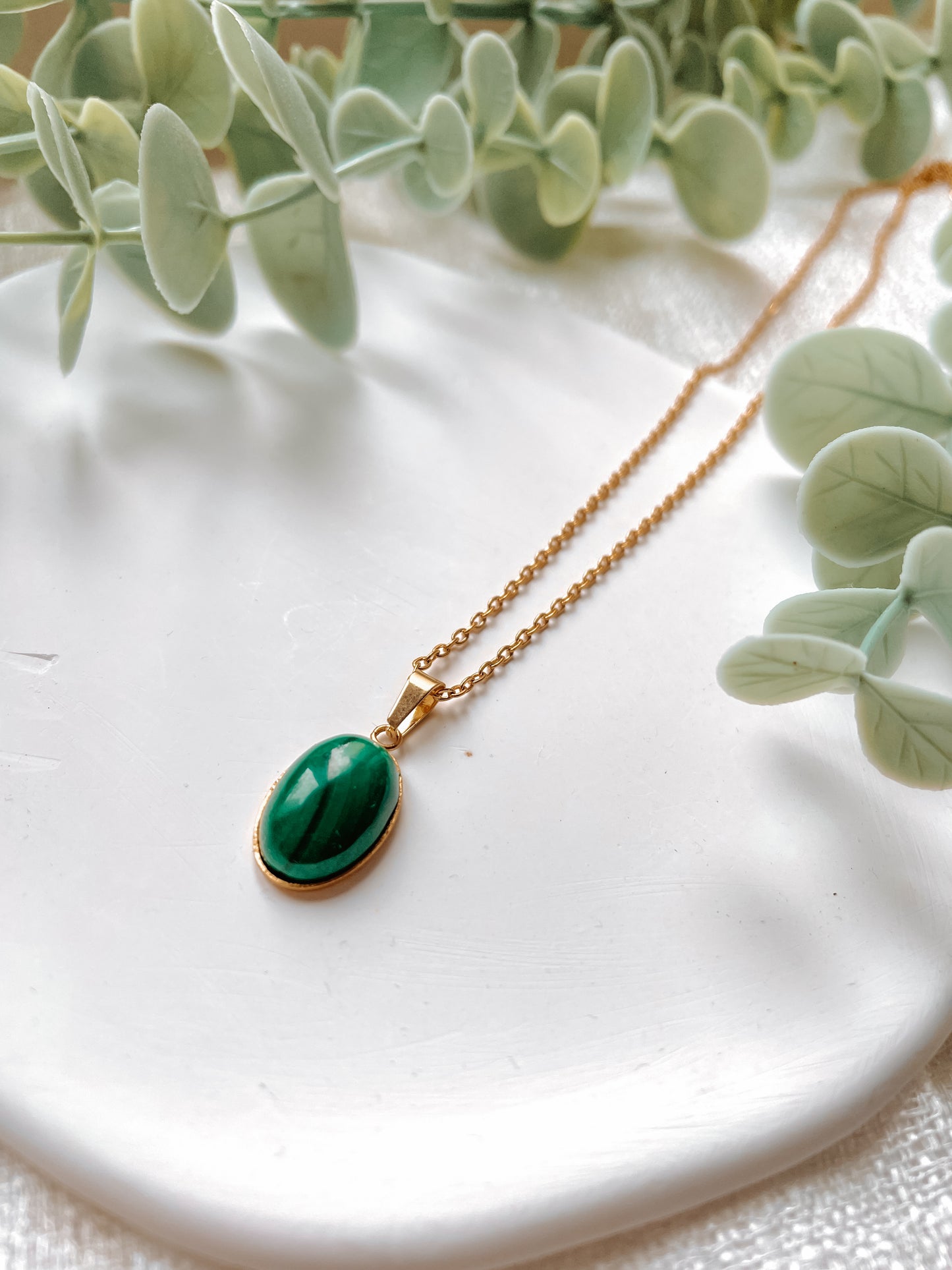 Handgemachte grüne Malachit-Kette mit ovalem Anhänger in Gold, liegend auf Tablett