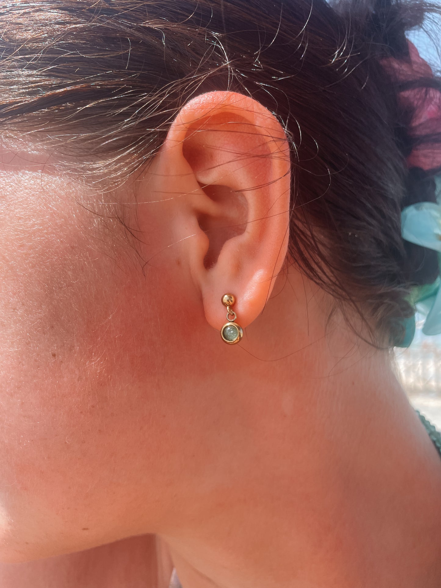 Goldene Stecker-Ohrringe mit runden, grünen Aventurin-Steinen am Ohr eines Models