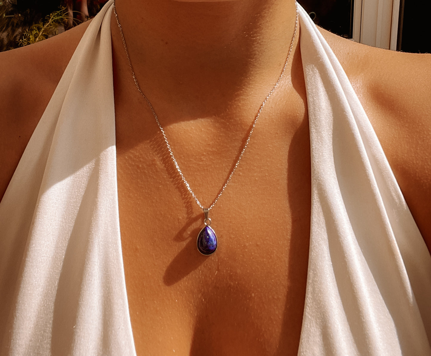 Tropfenförmiger blauer Lapislazuli-Anhänger an feiner Silberkette, am Dekolleté eines Modells gezeigt.