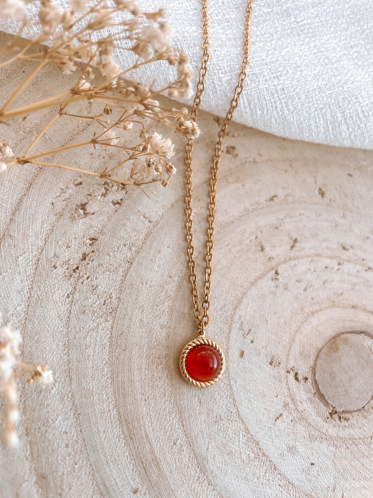 Handgemachte rote Karneol-Kette mit rundem Anhänger in Gold, liegend auf Tablett