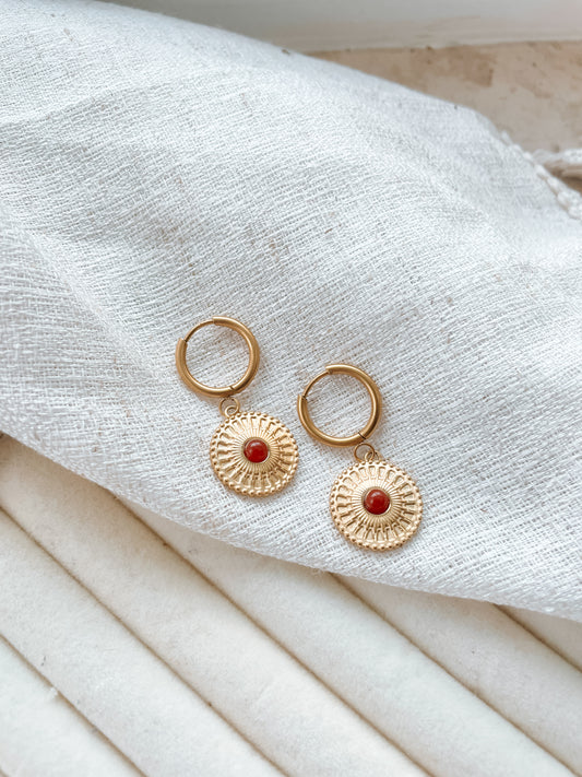 Goldene Creolen-Ohrringe mit runden, roten Karneol-Steinen und Medaillon Anhängern auf weißem Tuch