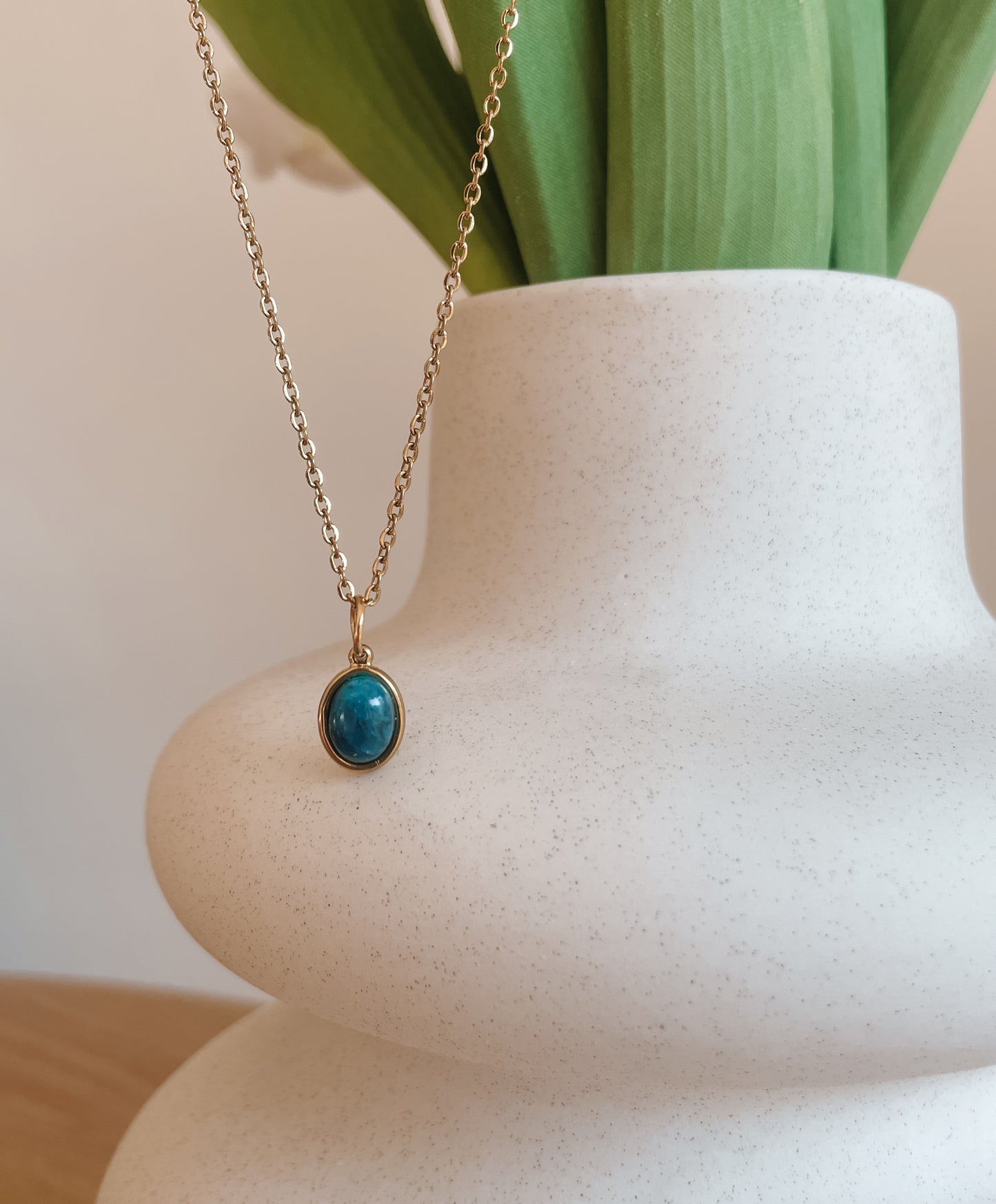 Handgemachte blaue Apatit-Kette mit ovalem Anhänger in Gold, hängend an einer Vase