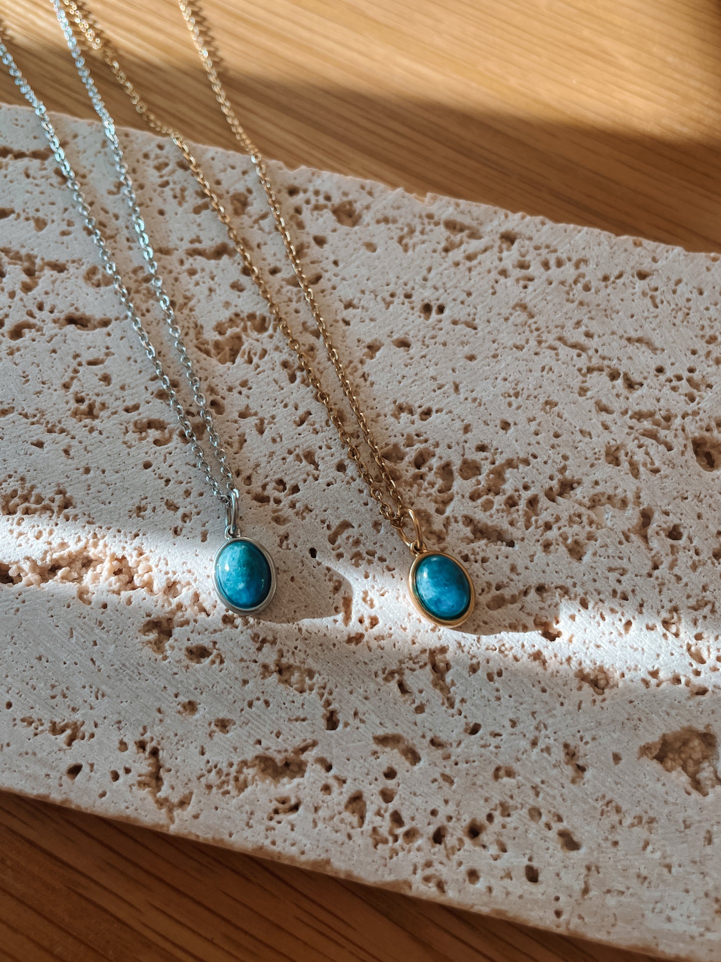 Handgemachte blaue Apatit-Ketten mit ovalem Anhänger in Gold und Silber, liegend auf Tablett