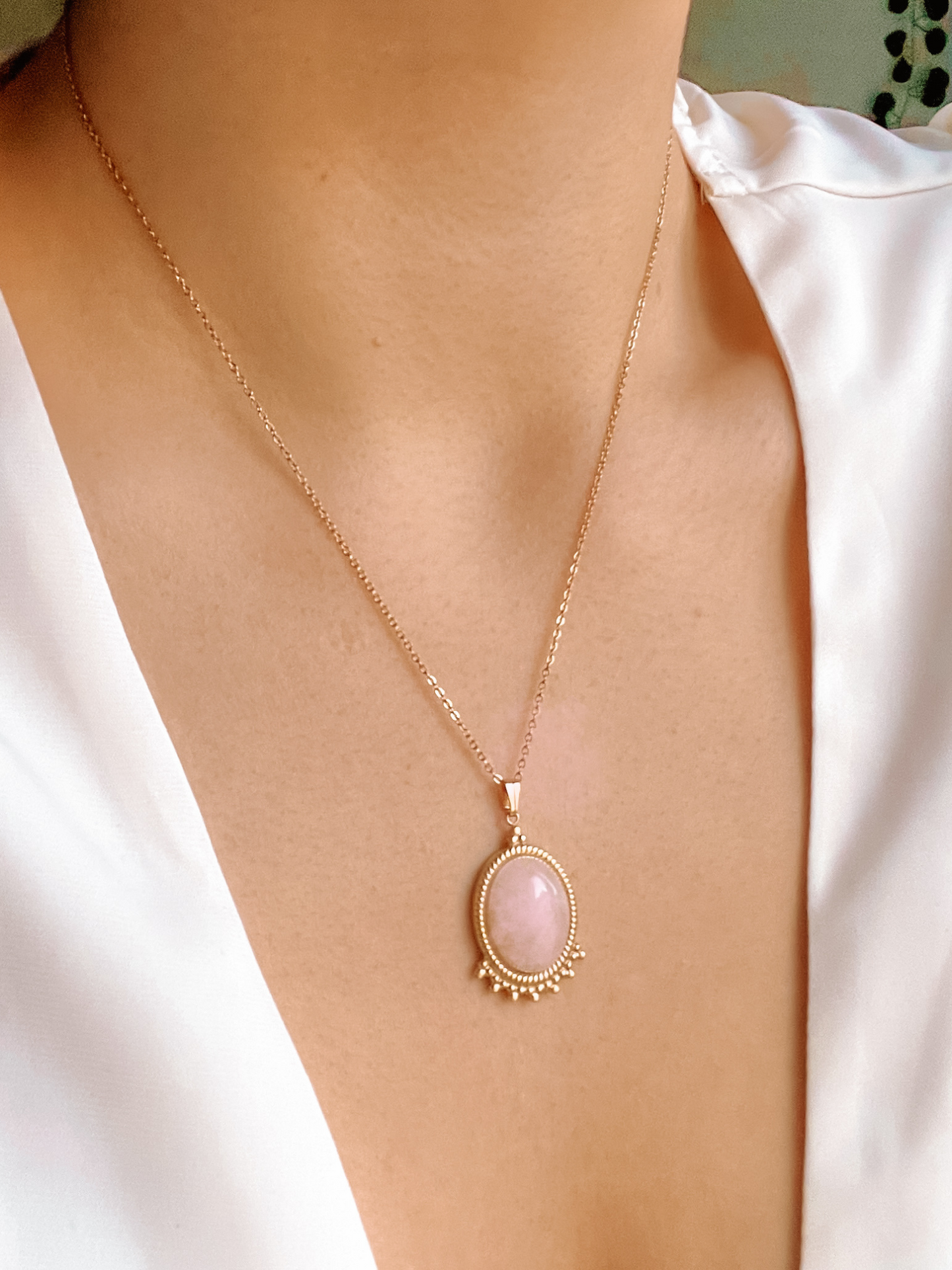 Ovaler rosa Rosenquarz-Anhänger an feiner Goldkette, am Hals eines Modells gezeigt.