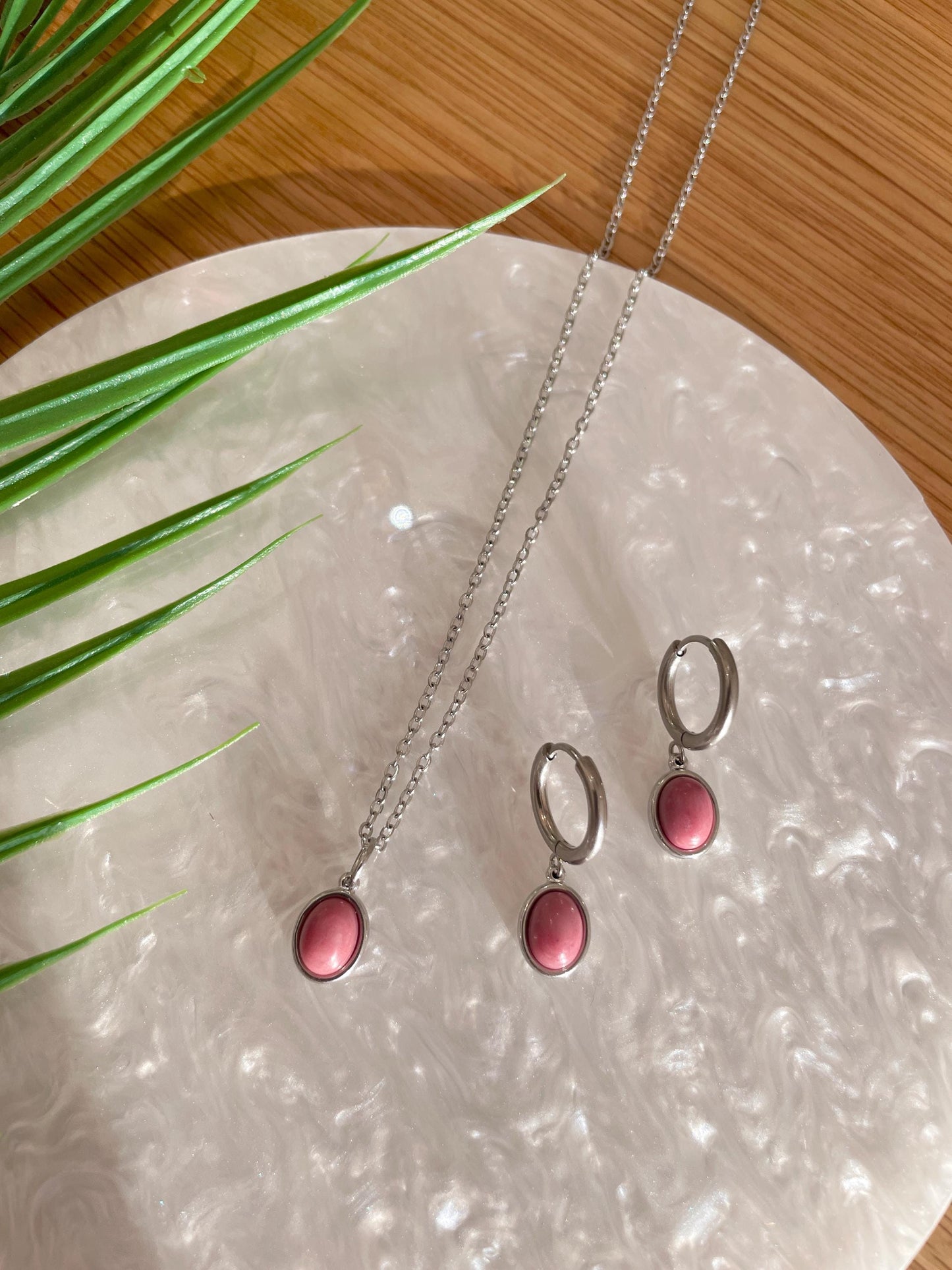 Silbernes Schmuckset mit Ohrring und Halskette mit rosa Rhodonit Anhängern liegend auf weißem Tablett