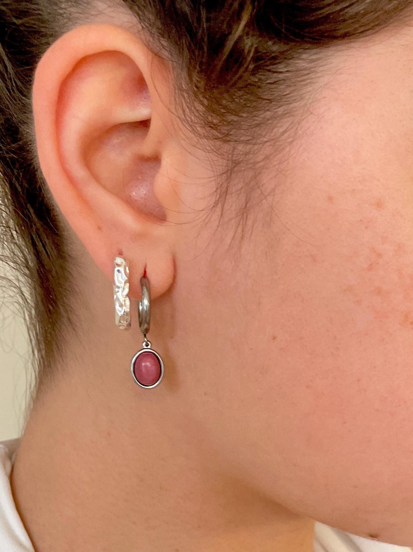 Silberne Creolen-Ohrringe mit ovalen, rosa Rhodonit-Steinen an Ohr eines Modells, Detailaufnahme