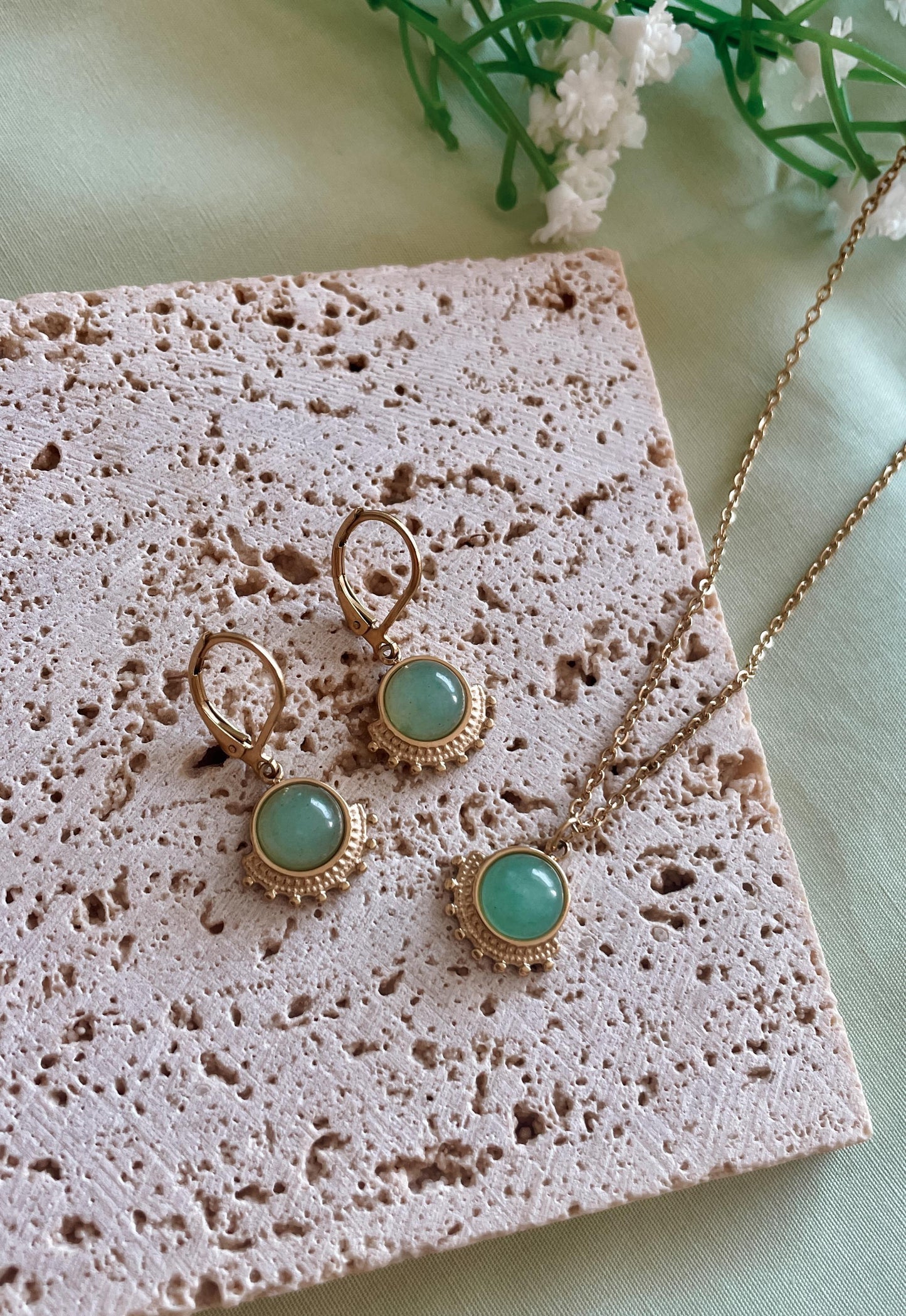 Goldenes Schmuckset mit Ohrring und Halskette mit grünen Aventurin Anhängern liegend auf Stein