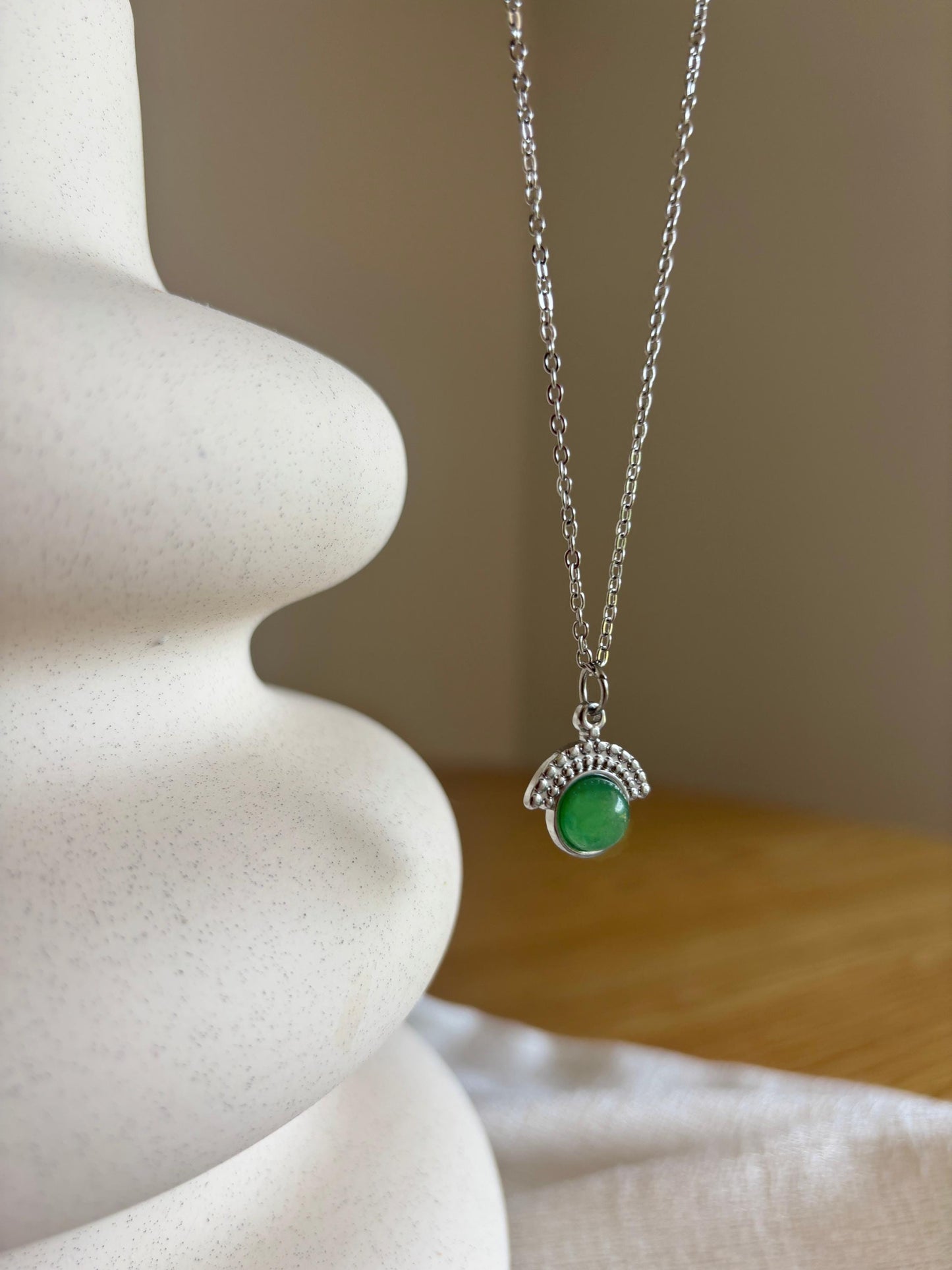Handgemachte grüne Aventurin-Kette mit rundem Anhänger in Silber, hängend an einer Vase