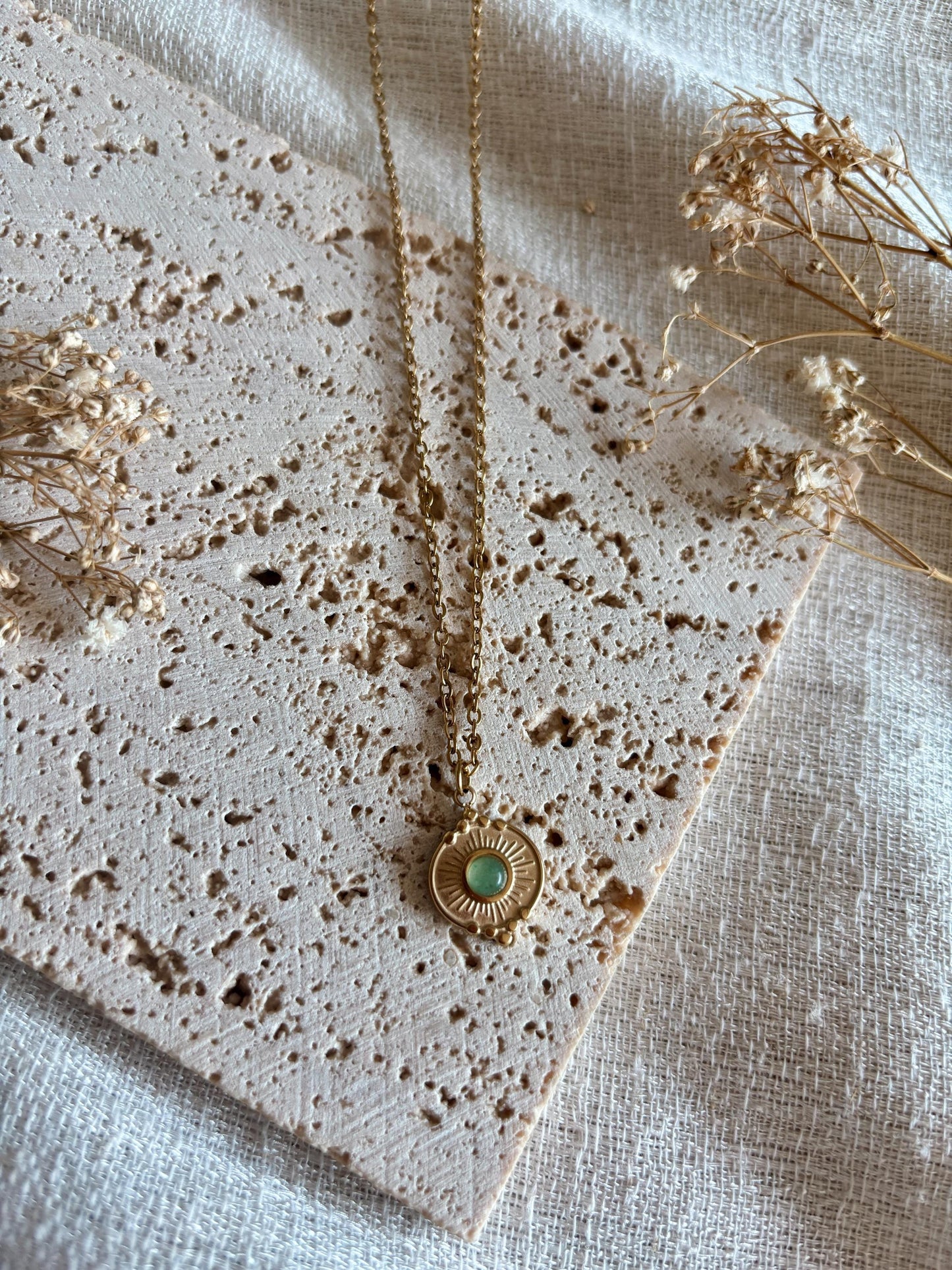 Handgemachte grüne Aventurin-Kette mit rundem Medaillon Anhänger in Gold, liegend auf Tablett