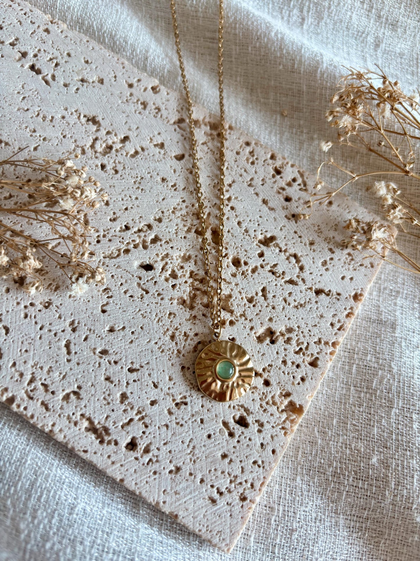 Handgemachte grüne Aventurin-Kette mit rundem Medaillon Anhänger in Gold, liegend auf Tablett