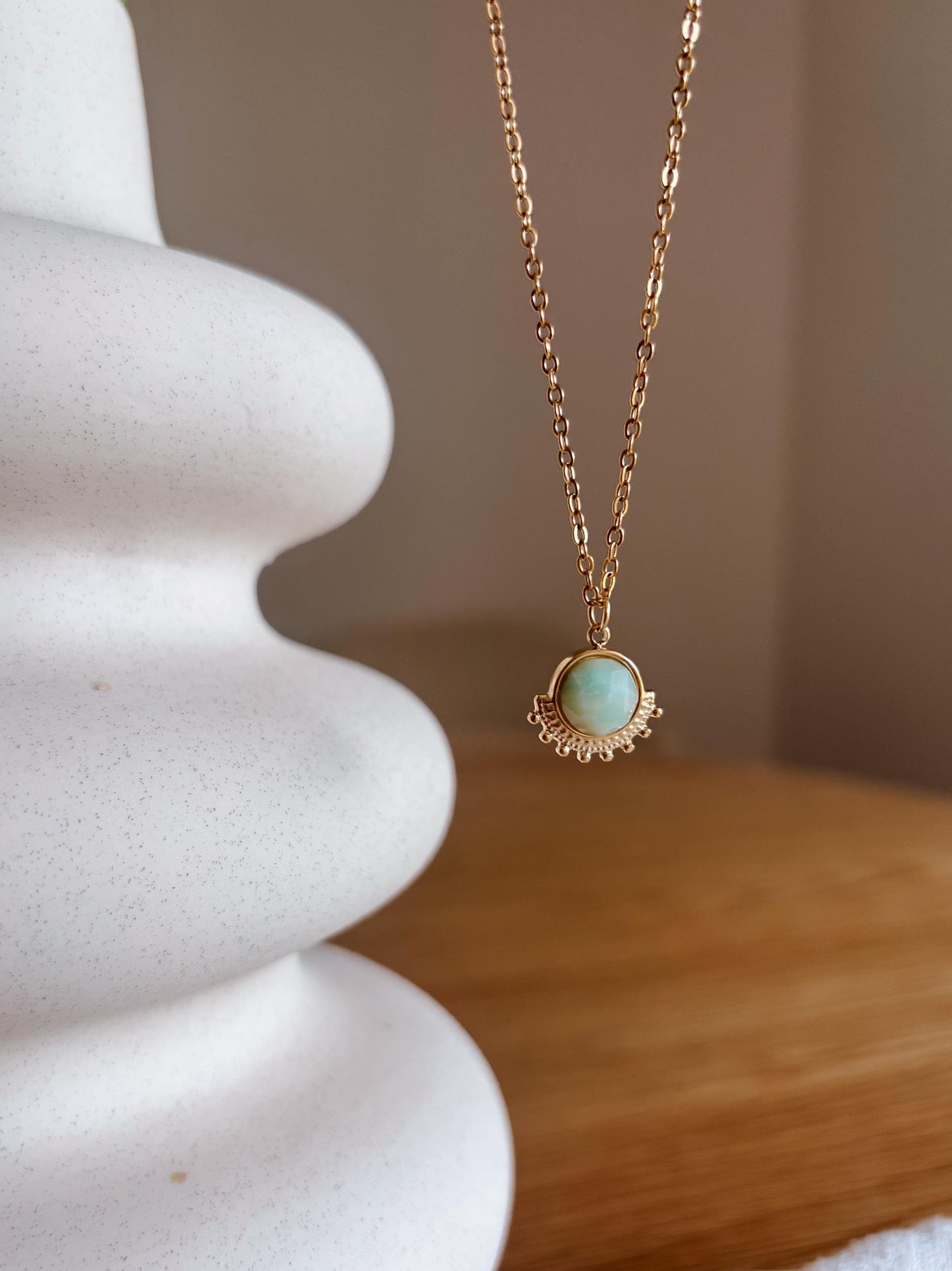 Handgemachte hellblaue Amazonit-Kette mit rundem Anhänger in Gold, hängend an Vase