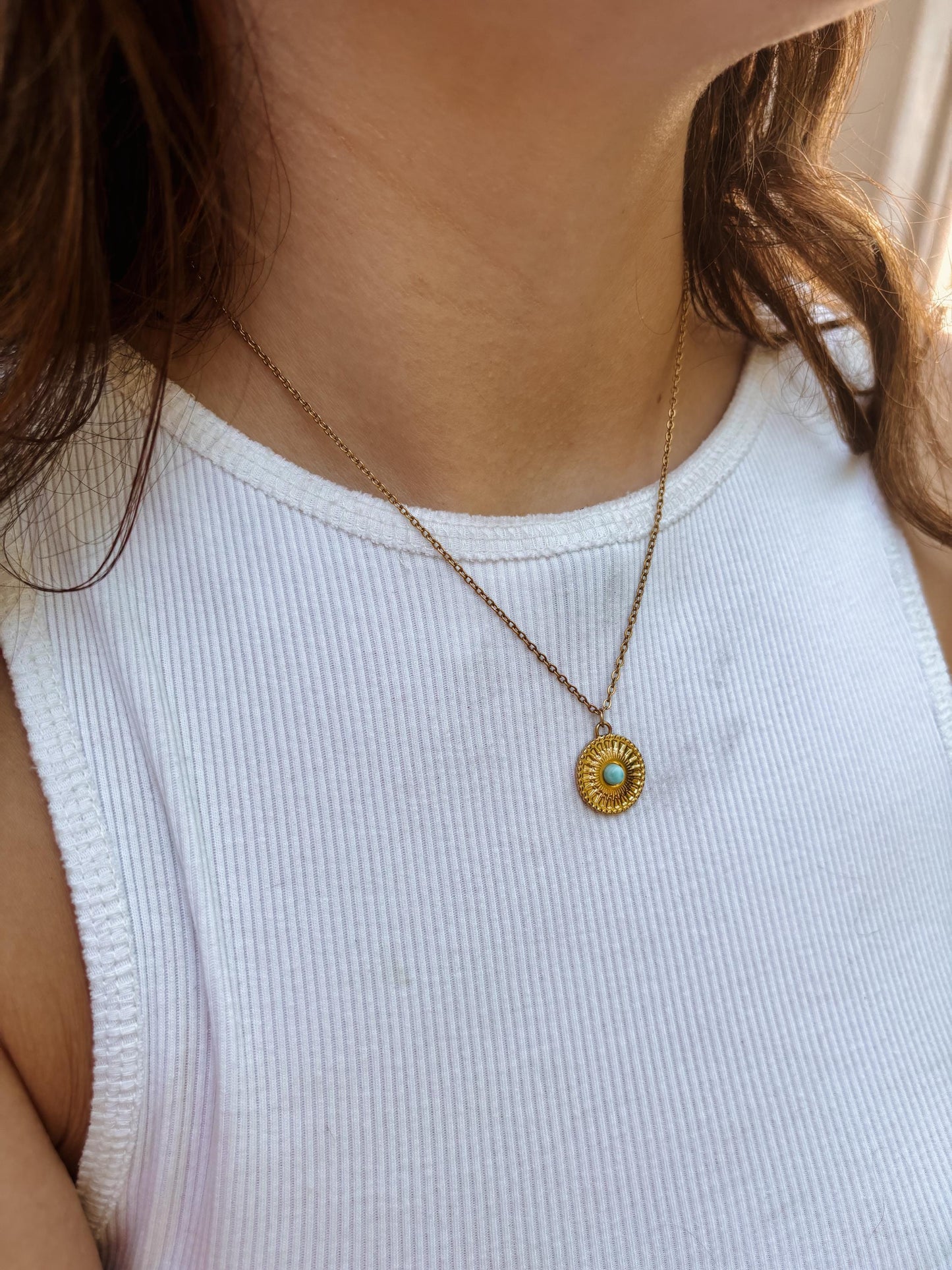 Ovaler hellhellblauer Larimar-Anhänger an feiner Medaillon Goldkette, am Dekolleté eines Modells gezeigt.