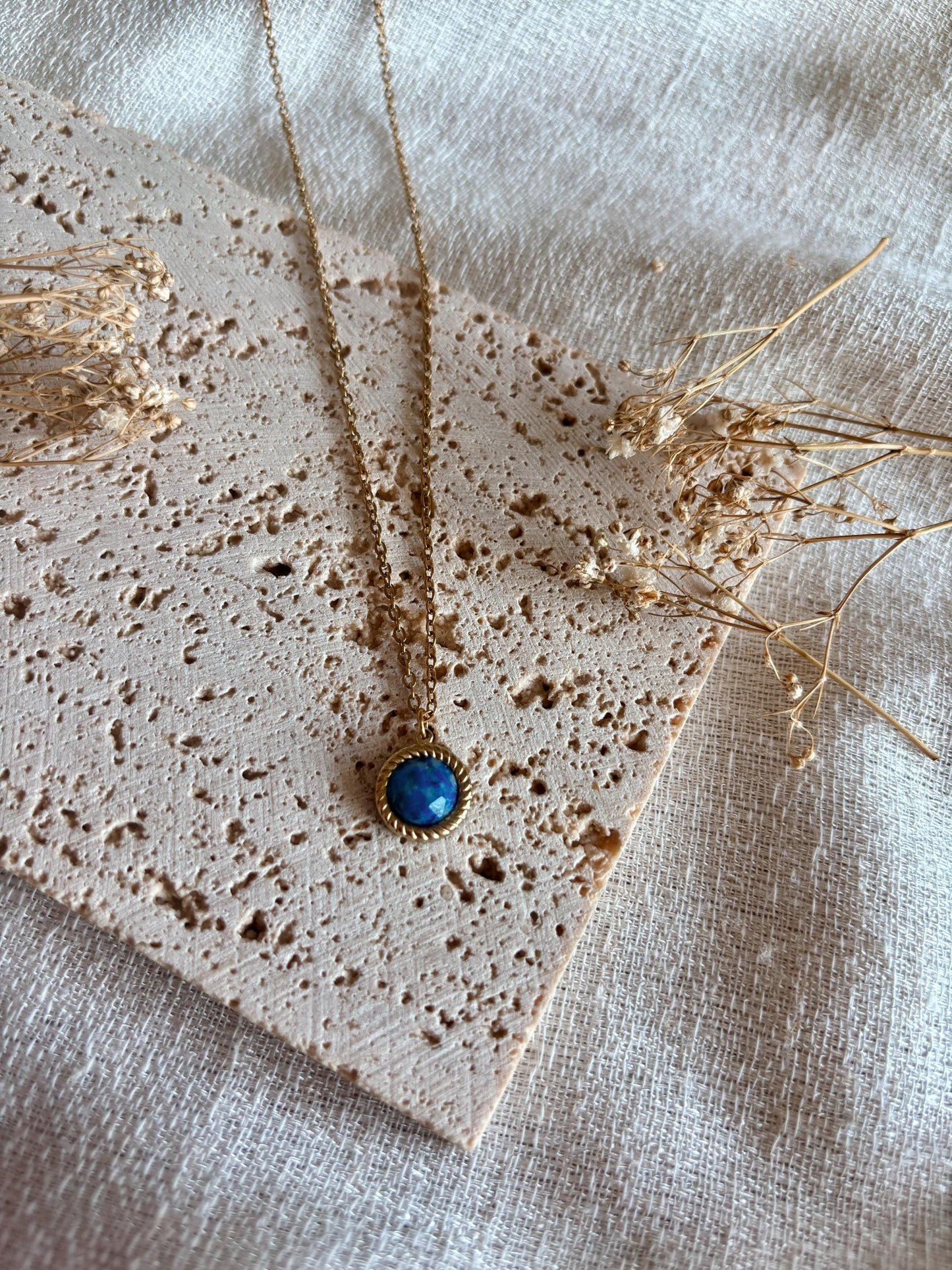Handgemachte blaue Lapislazuli-Kette mit rundem Anhänger in Gold, liegend auf Tablett