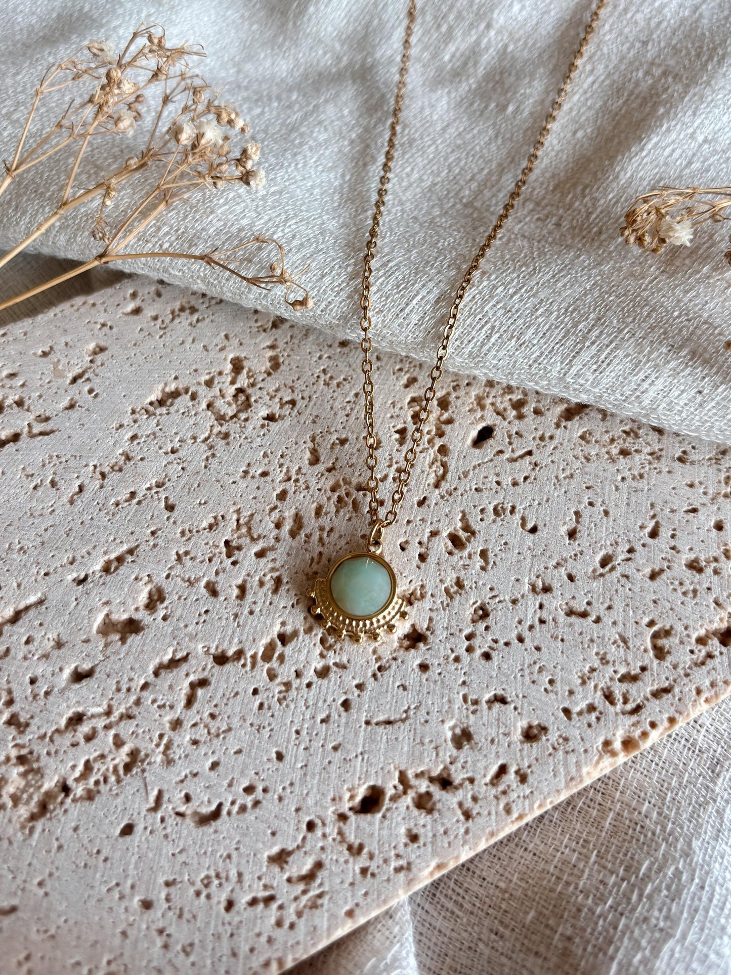 Handgemachte hellblaue Amazonit-Kette mit rundem facettierten Anhänger in Gold, liegend auf Tablett