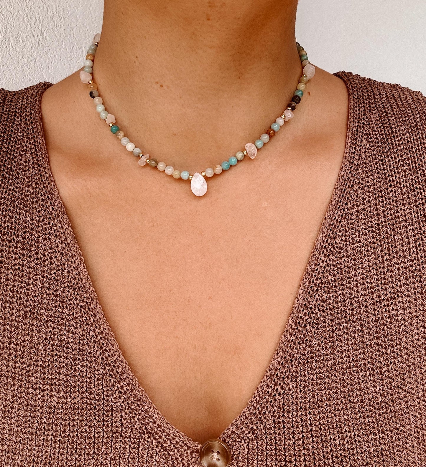 Blaue Amazonit-Perlenkette mit einem weißen facettierten Mondstein Anhänger am Dekollete eines Modells mit Häkeltop