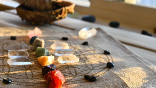Bunte Steine sind auf einem Tuch in einem Muster arrangiert, passend zur Chakra-Heilung.