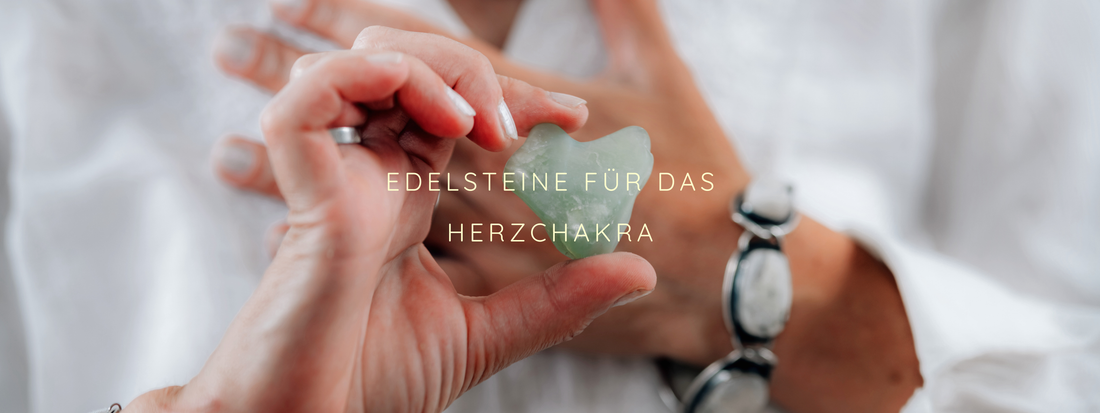 Person hält einen grünen Edelstein in Herzform vor sich. Text: "Edelsteine für das Herzchakra". Hintergrund ist eine weiße Kleidung.