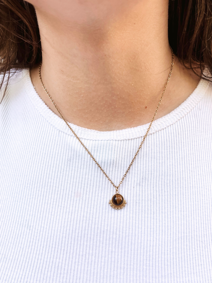 Kette mit goldenem verziertem Anhänger mit braunem Tigerauge Stein am Hals eines Models