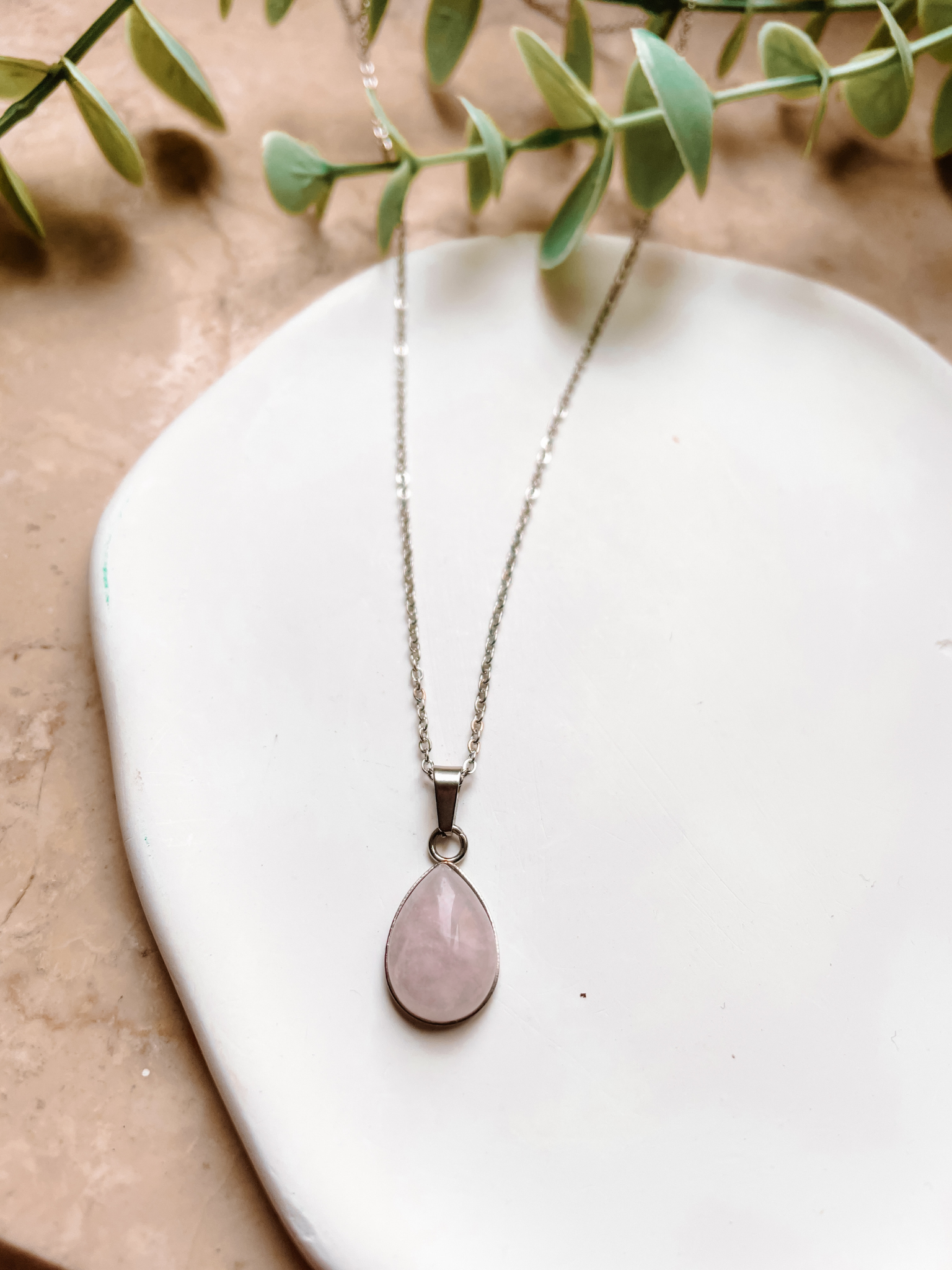 Handgemachte rosa Rosenquarz-Kette mit Tropfen Anhänger in Silber,  liegend auf Tablett