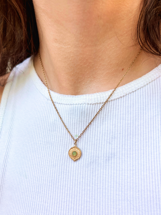 Kette mit goldenem verziertem Münze Anhänger mit grünem Aventurin Stein am Hals eines Models