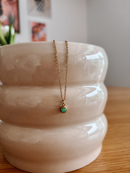 Handgemachte grüne Aventurin-Kette mit winzigem runden Anhänger in Gold, hängend an einer Vase