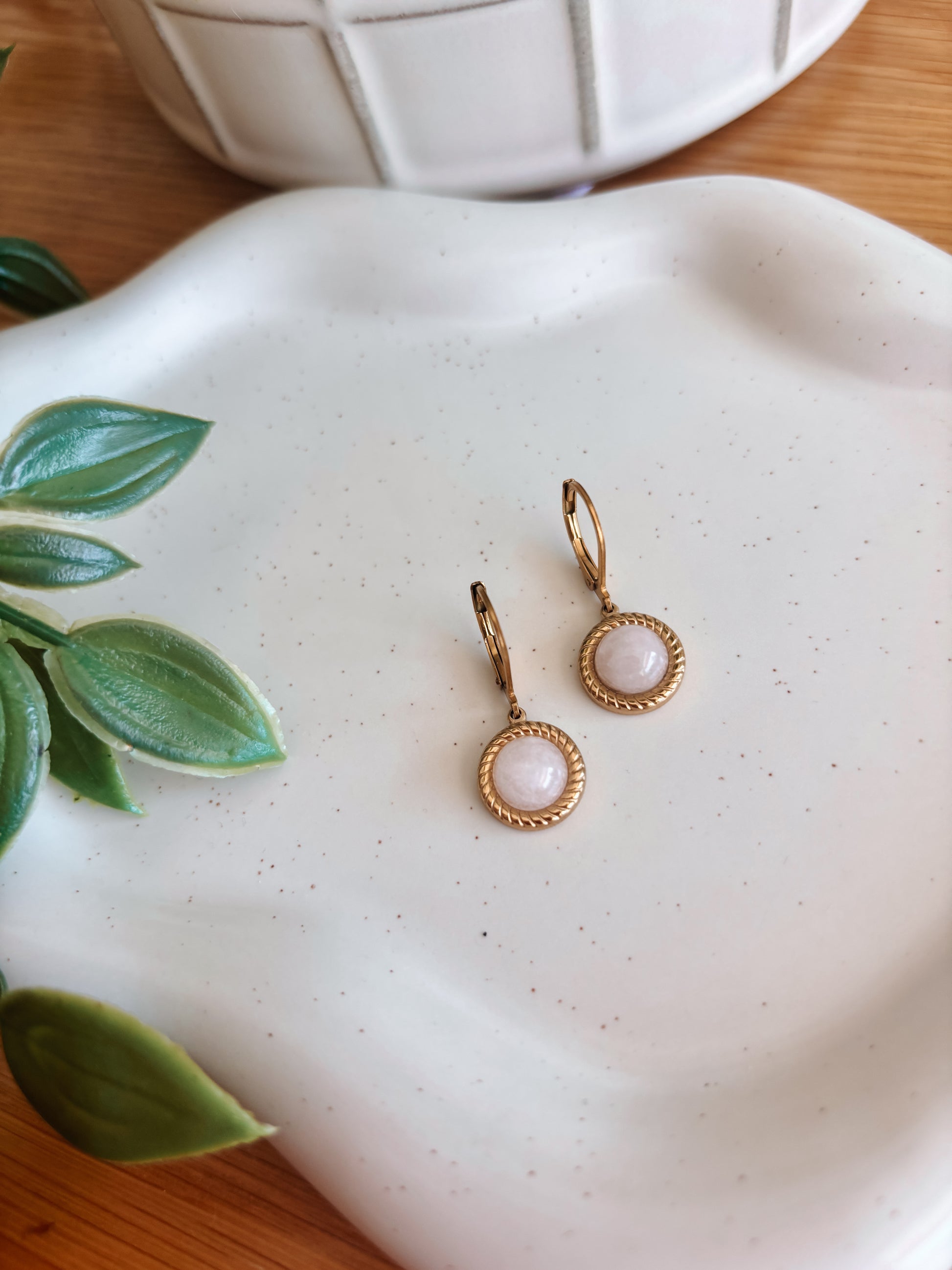 Goldene Creolen-Ohrringe mit runden, rosa Rosenquarz-Steinen auf Tablett, Detailaufnahme