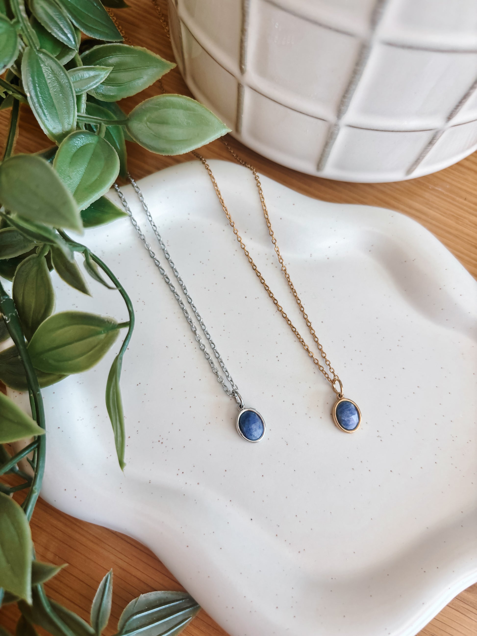 Handgemachte blaue Lapis-Lazuli-Ketten mit ovalem Anhänger in Gold und Silber, liegend auf Tablett