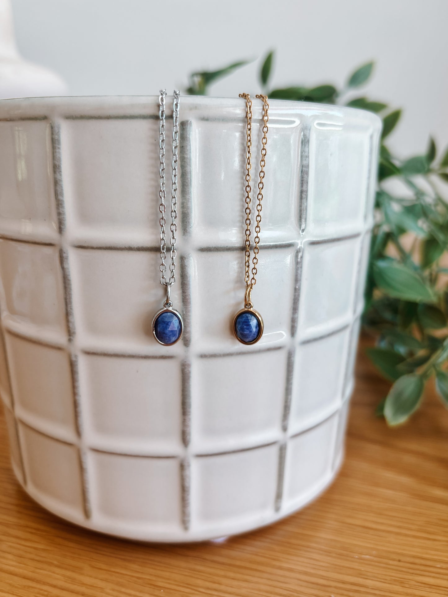 Handgemachte blaue Lapis-Lazuli-Ketten mit ovalem Anhänger in Gold und Silber, hängend an einer Vase