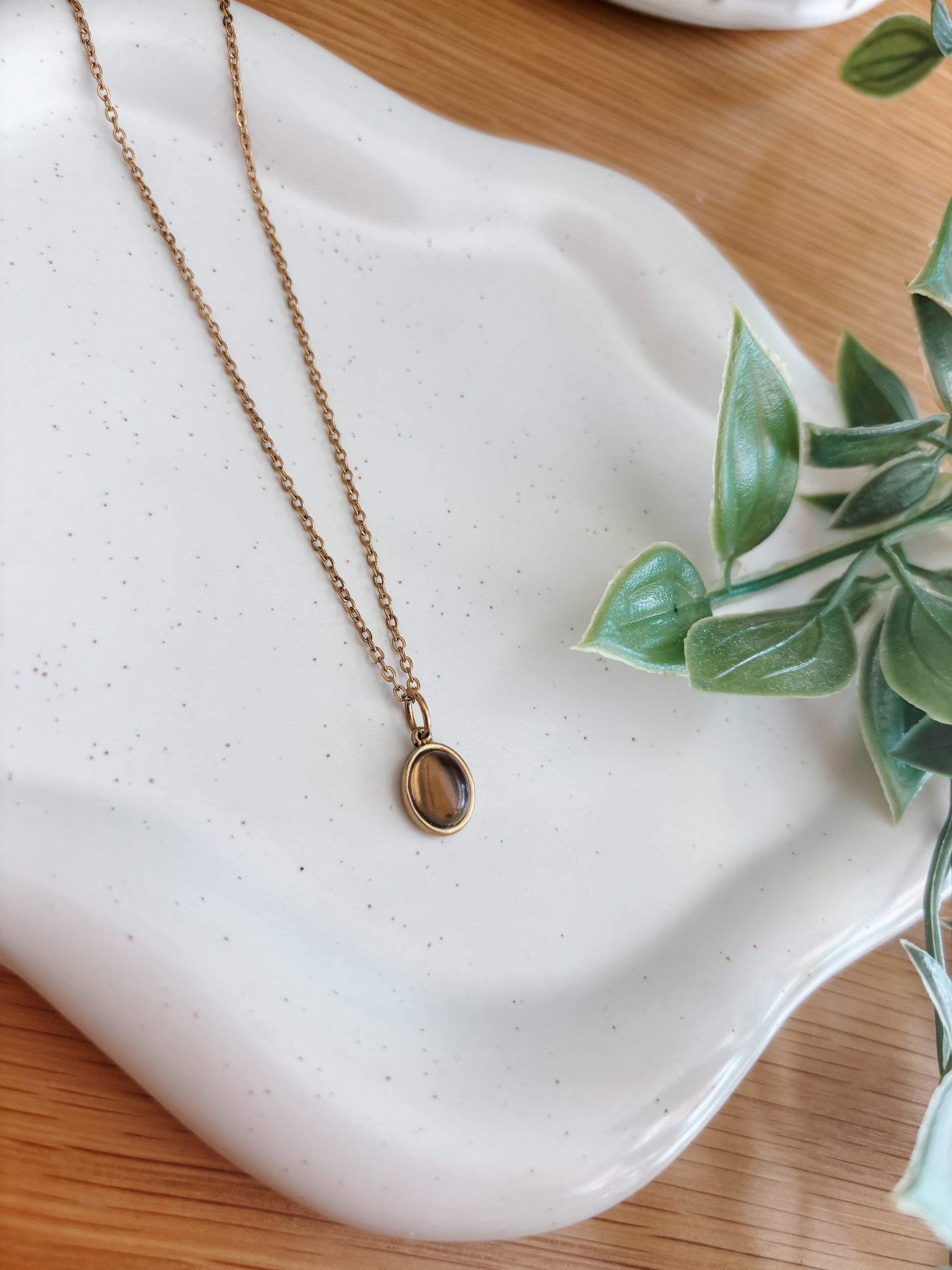 Handgemachte braune Rauchquarz-Kette mit ovalem Anhänger in Gold,  liegend auf Tablett