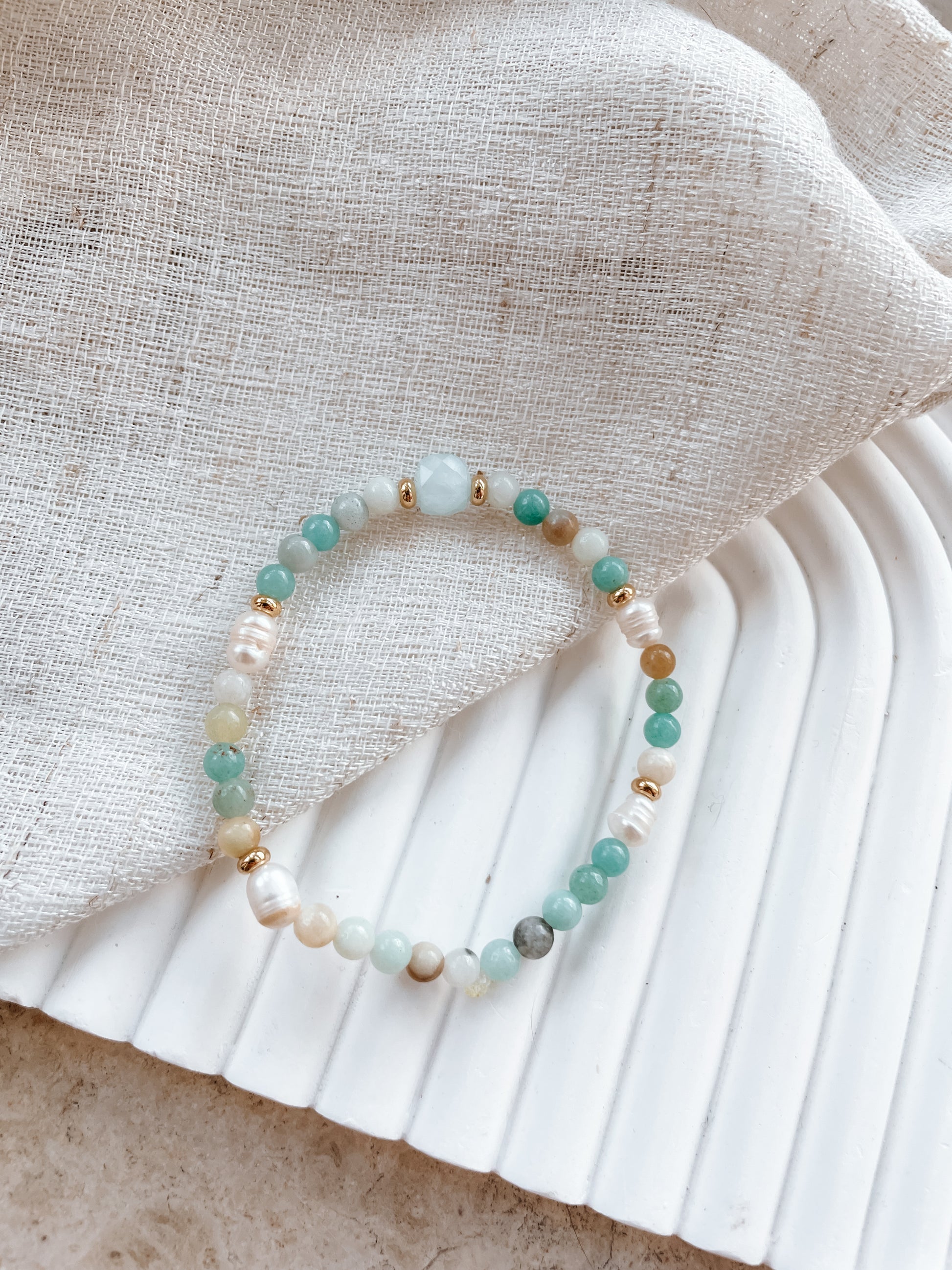 Blaues Amazonit-Perlenarmband in Gold mit Aquamarin Stein liegend auf Tuch