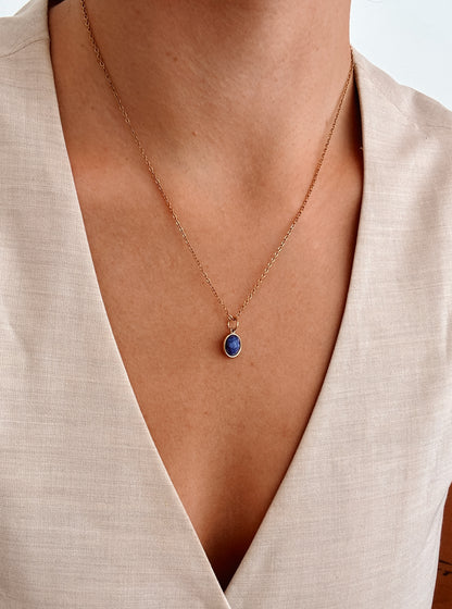 Ovaler blauer Lapis-Lazuli-Anhänger an feiner Goldkette, am Dekolleté eines Modells gezeigt.
