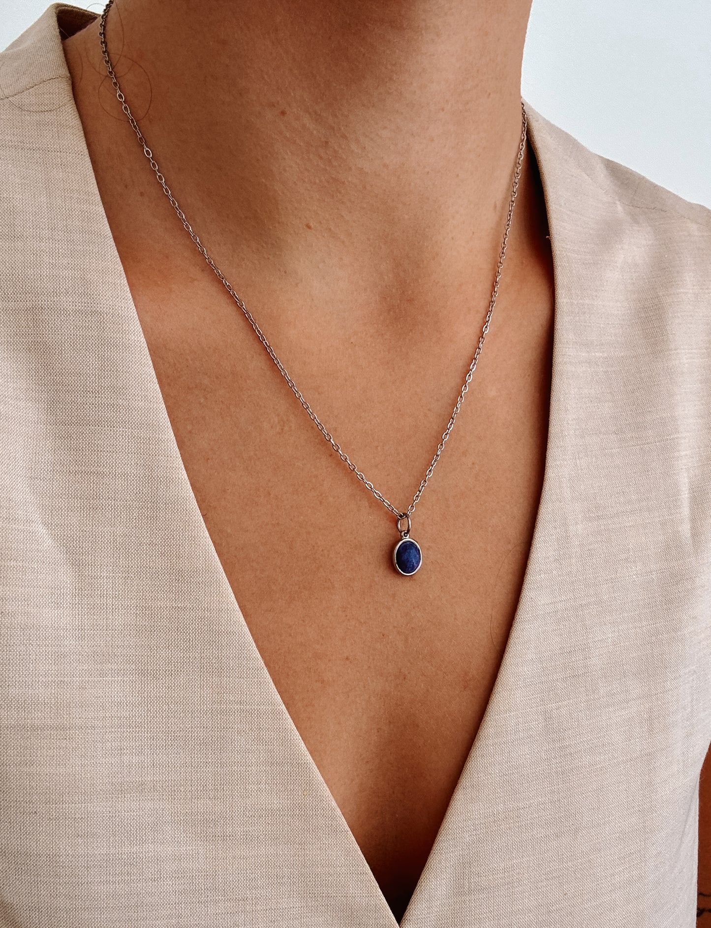 Ovaler blauer Lapis-Lazuli-Anhänger an feiner Silberkette, am Dekolleté eines Modells gezeigt.