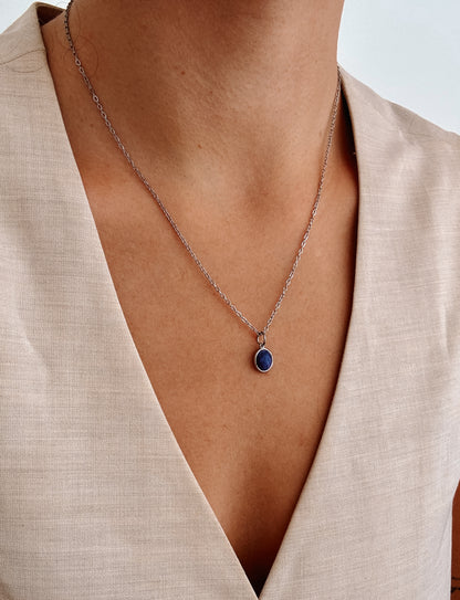 Ovaler blauer Lapis-Lazuli-Anhänger an feiner Silberkette, am Dekolleté eines Modells gezeigt.
