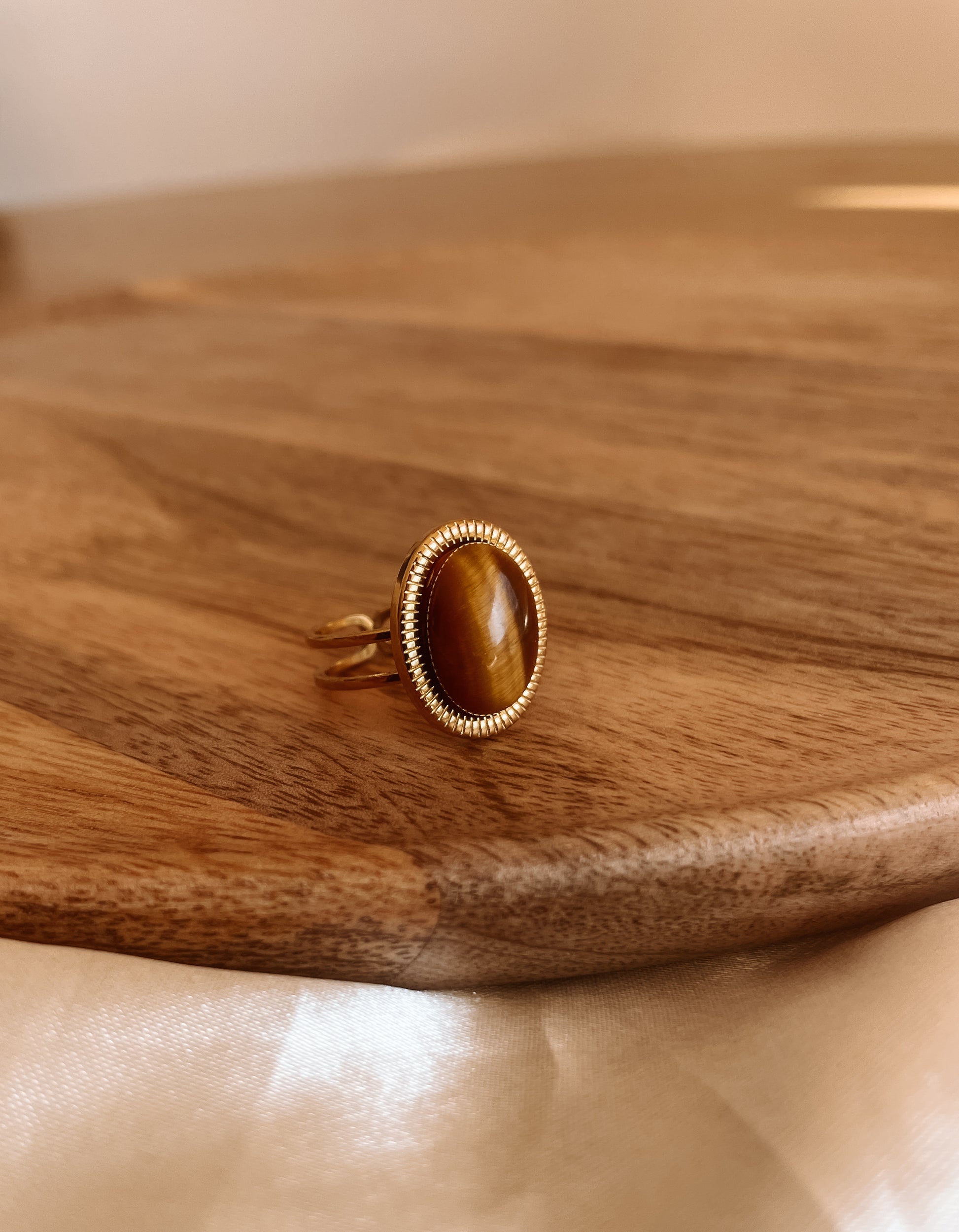 Boho Goldring mit ovalem braunem Tigerauge-Stein an Holz Platte
