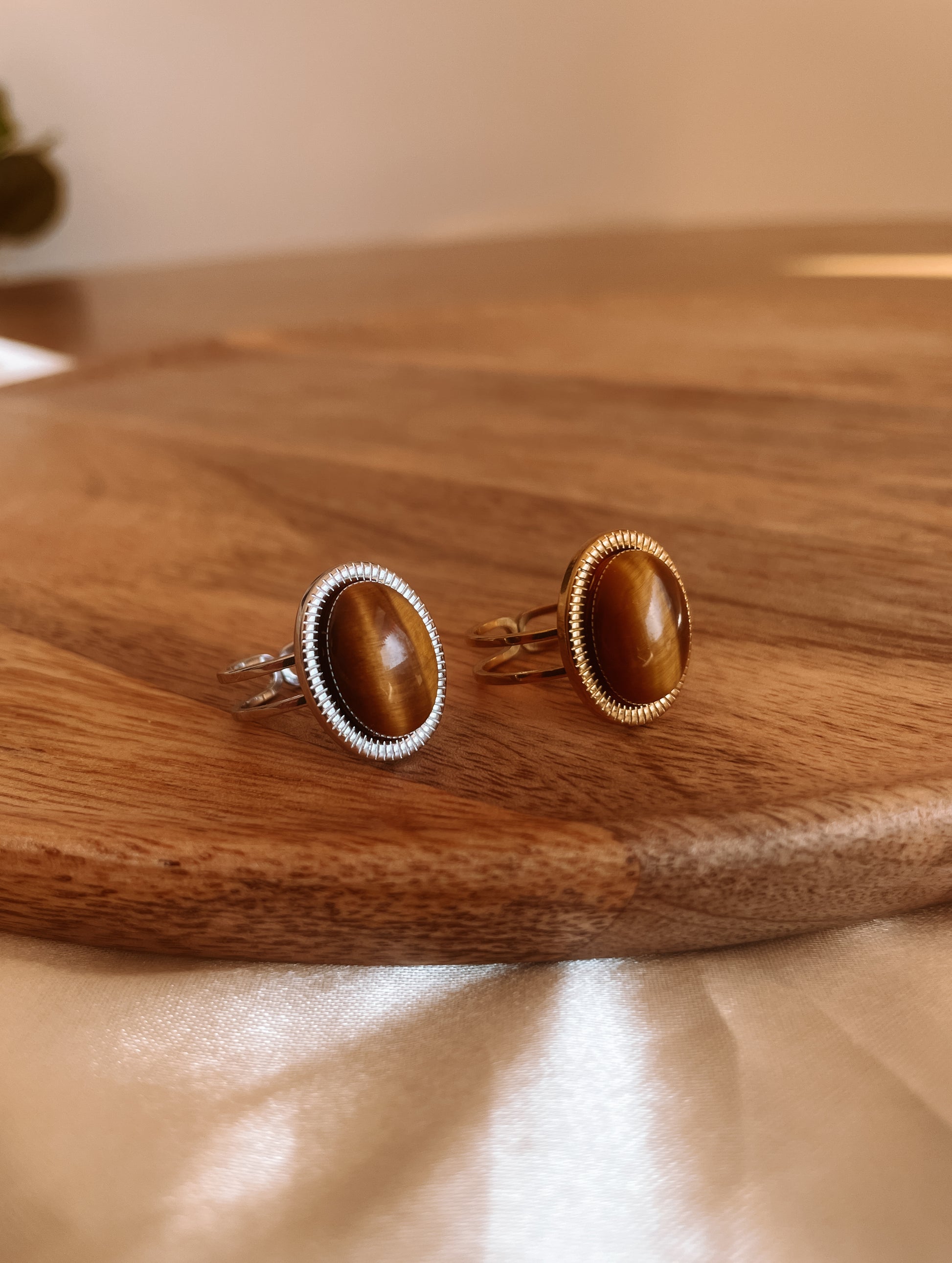 Boho Ringe in Gold und Silber mit ovalem braunem Tigerauge-Stein auf Holz Platte