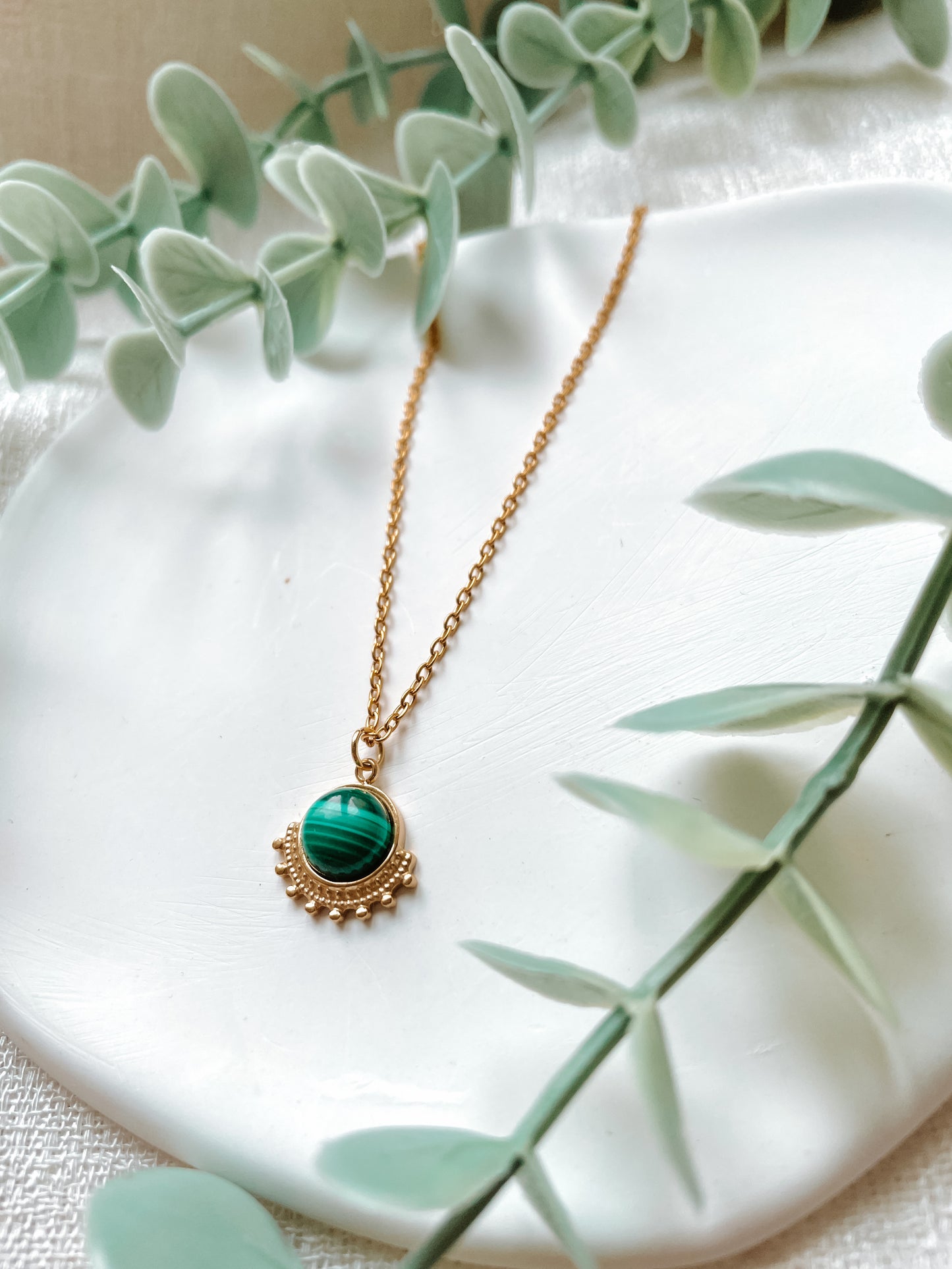Handgemachte grüne Malachit-Kette mit rundem Anhänger in Gold,  liegend auf Tablett