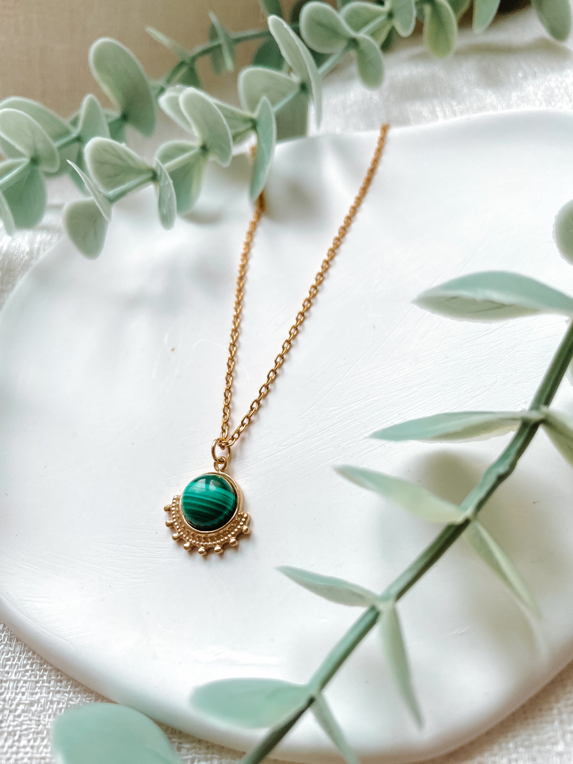 Handgemachte grüne Malachit-Kette mit rundem Anhänger in Gold,  liegend auf Tablett