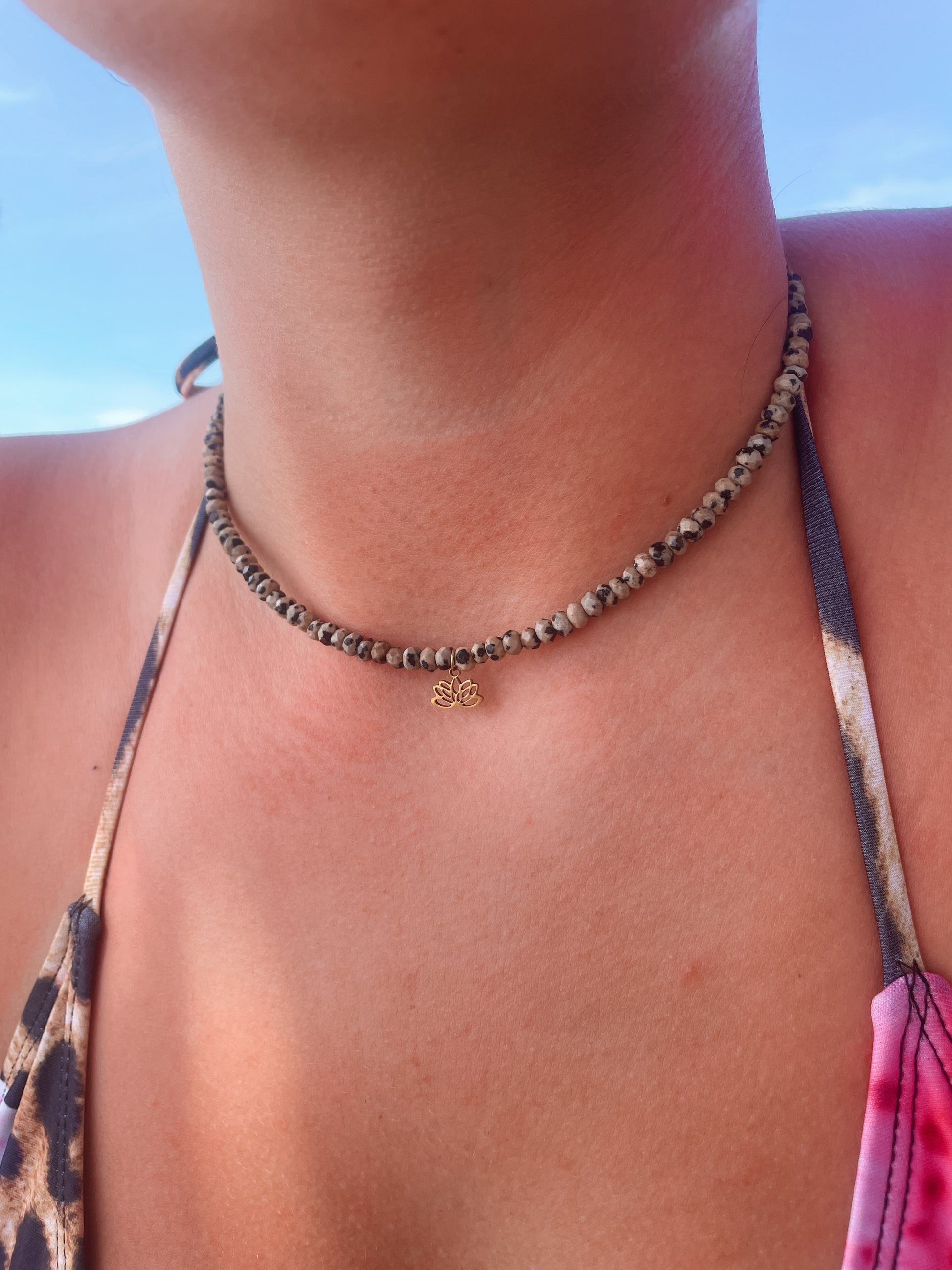 gepunktete Dalmatiner Jaspis-Perlenkette mit goldenem Lotusblume Anhänger am Hals eines Models