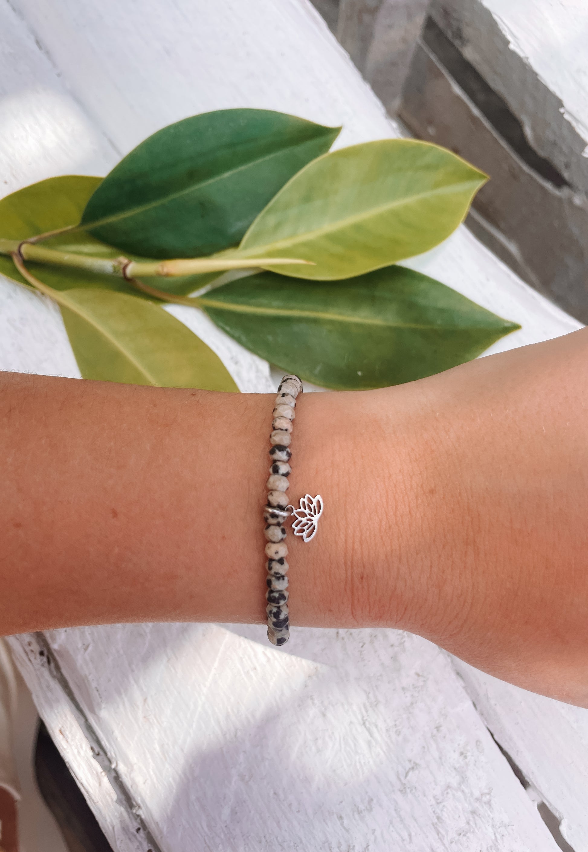 gepunktetes Dalmatiner Jaspis-Perlenarmband in Silber mit Lotusblüte Anhänger an Hand