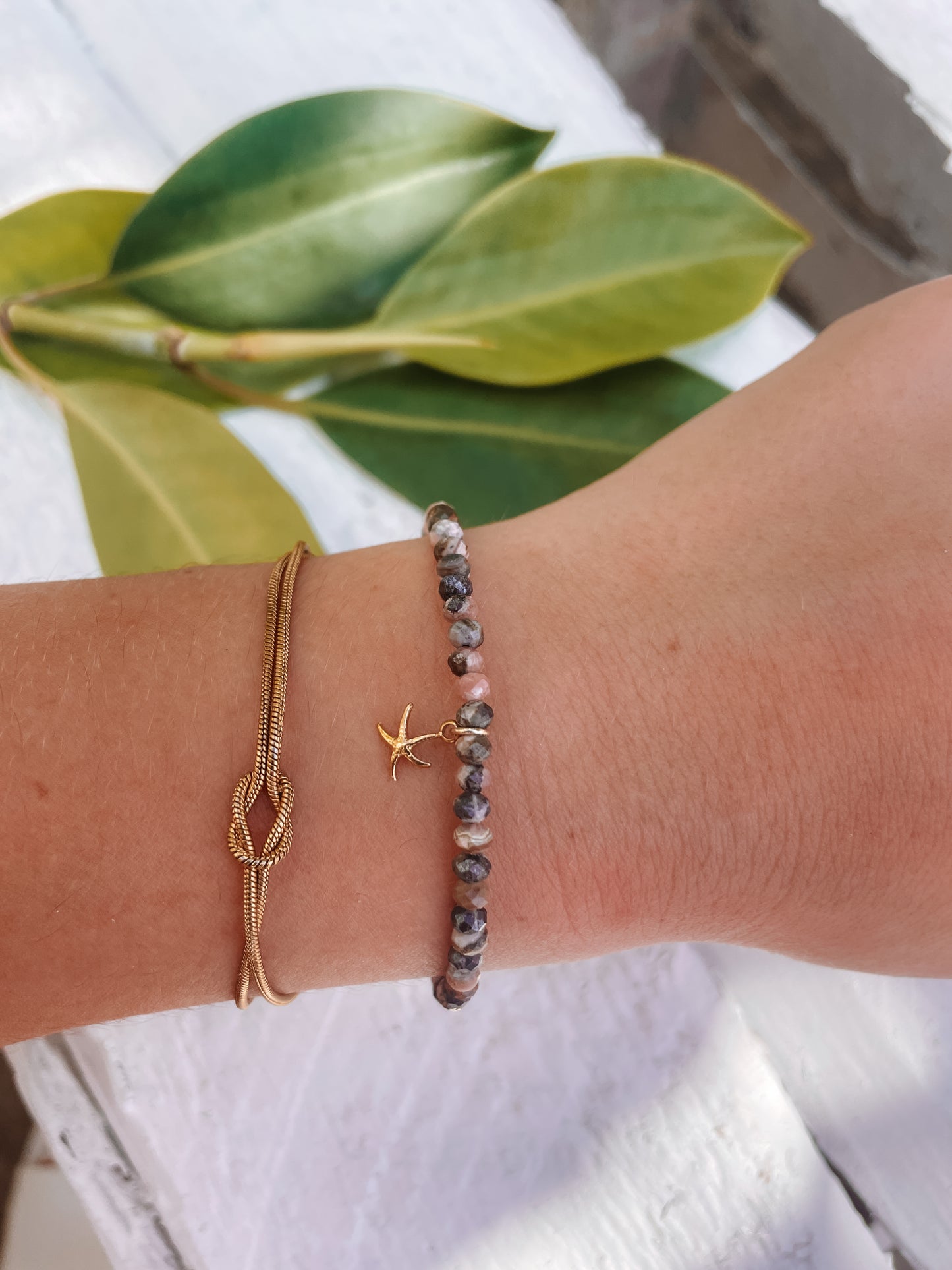 Rosa Braunes Rhodonit-Perlenarmband mit goldenem Seestern Anhänger an Hand