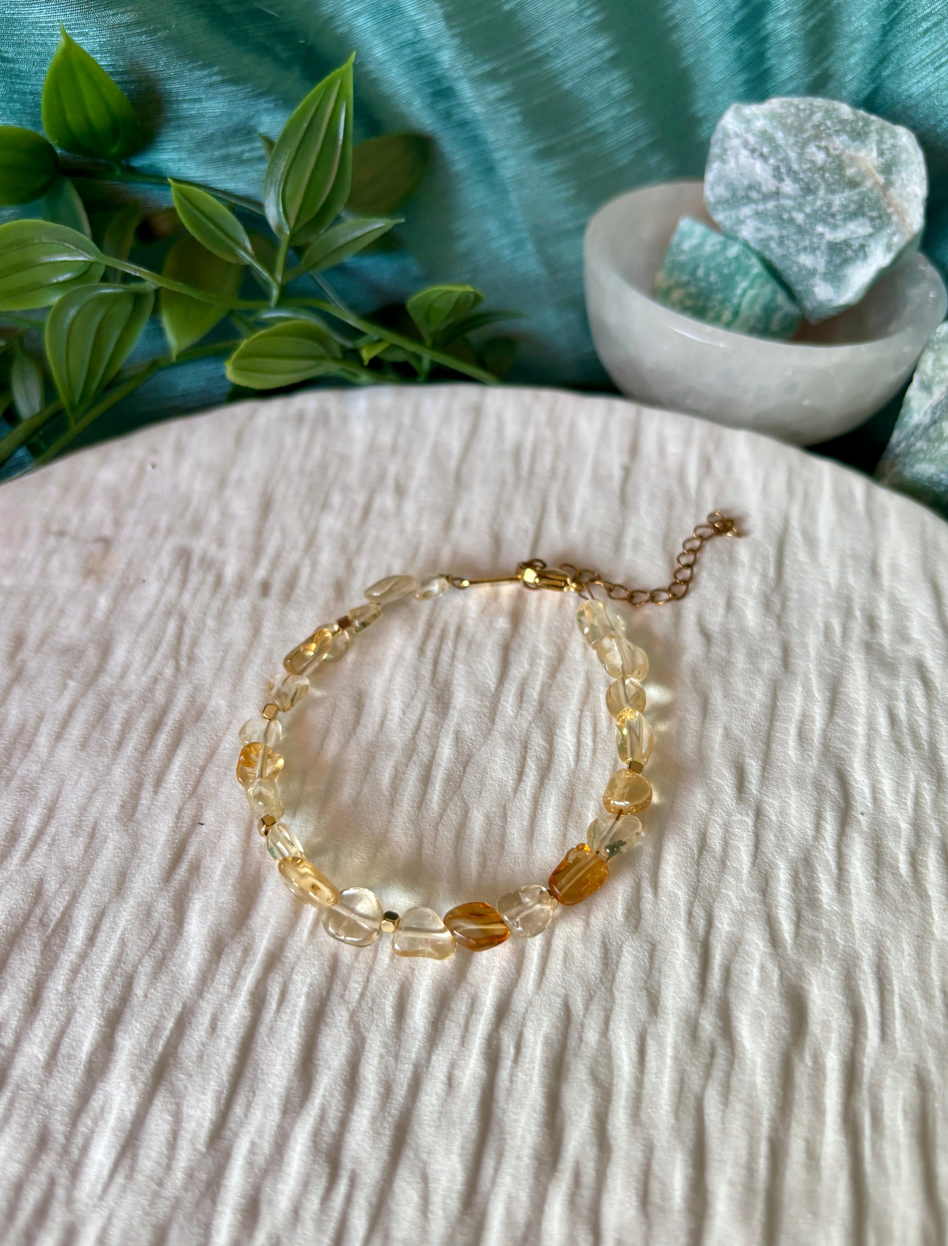 Goldenes Citrin Perlenarmband mit gelben Natursteinen liegend auf weißem Tablett, Ansicht von oben