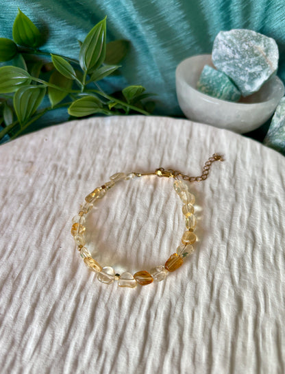 Goldenes Citrin Perlenarmband mit gelben Natursteinen liegend auf weißem Tablett, Ansicht von oben