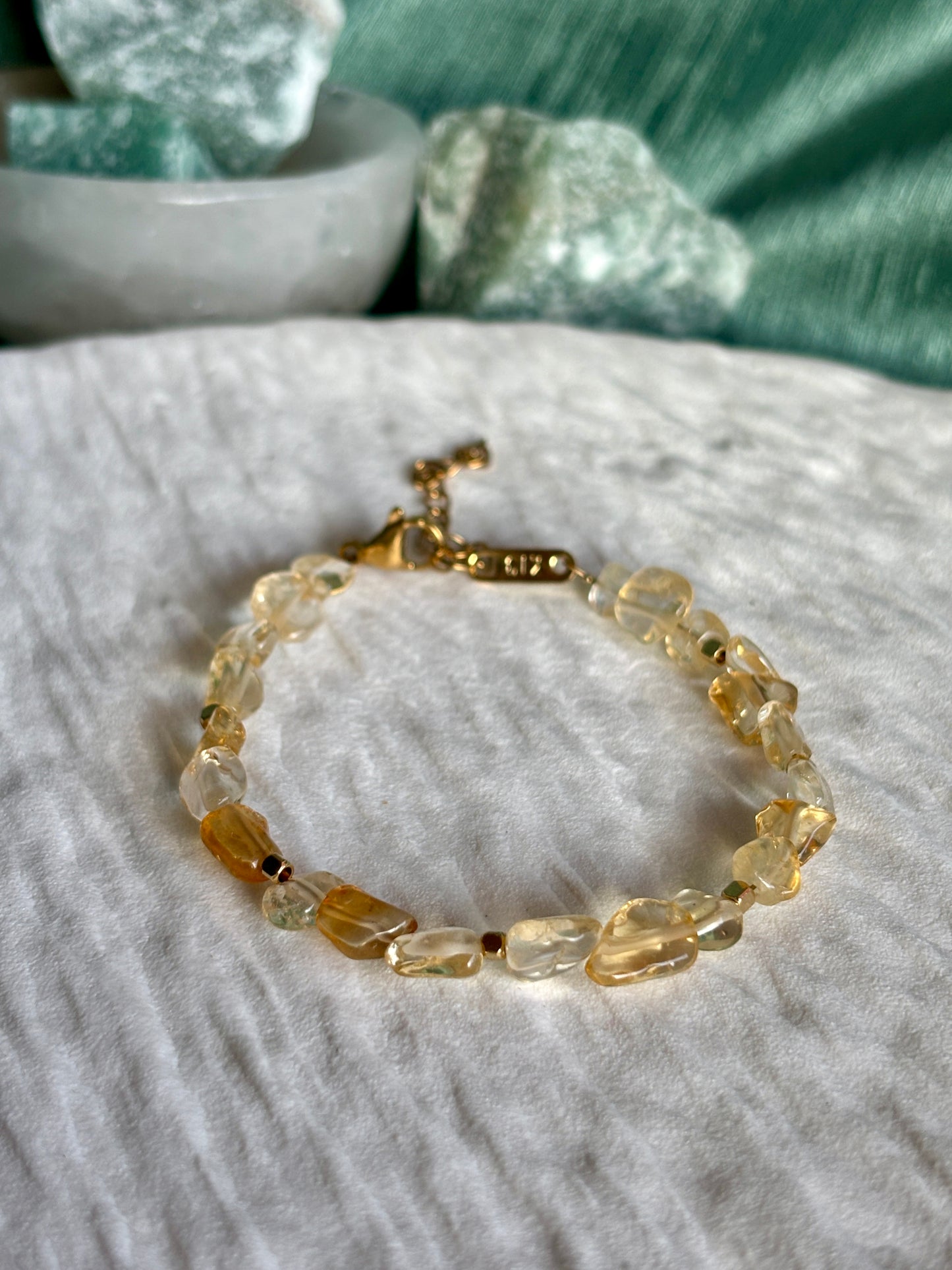 Goldenes Citrin Perlenarmband mit gelben Natursteinen liegend auf weißem Tablett, Detailaufnahme