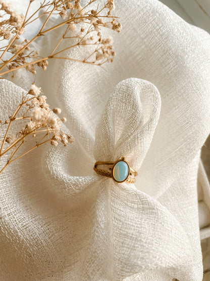 Goldring mit ovalem blauen Opalith-Stein auf weißem Tuch