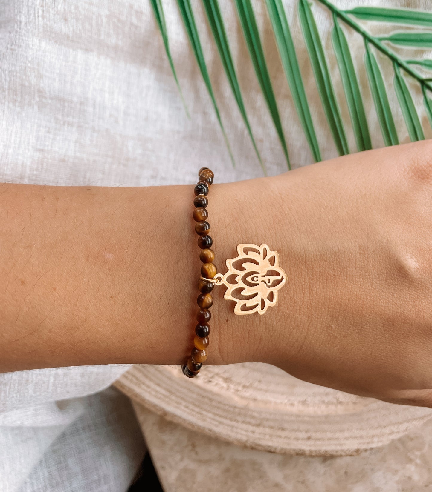 braunes Tigerauge-Perlenarmband in Gold mit Yoga Lotusblume Anhänger an Hand